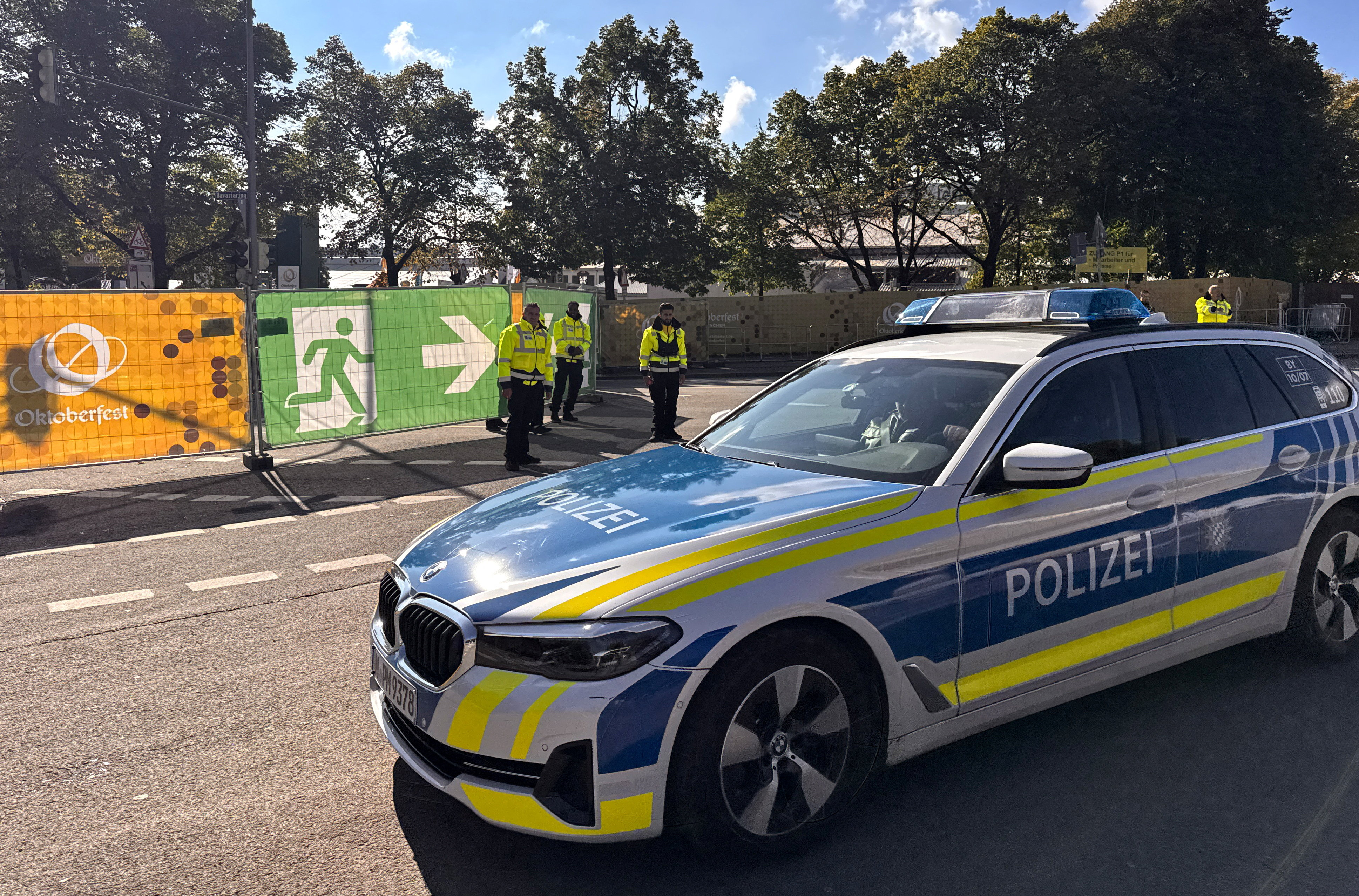 A police vehicle drives past security guards in front of a Theresienwiese entrance as the Oktoberfest beer festival will remain shut until at least 5 pm (1500 GMT) today, after police said they discovered explosives in a residential building in the north of the city that caught fire and left one person dead in Munich, Germany, October 1, 2025. REUTERS/Christine Uyanik