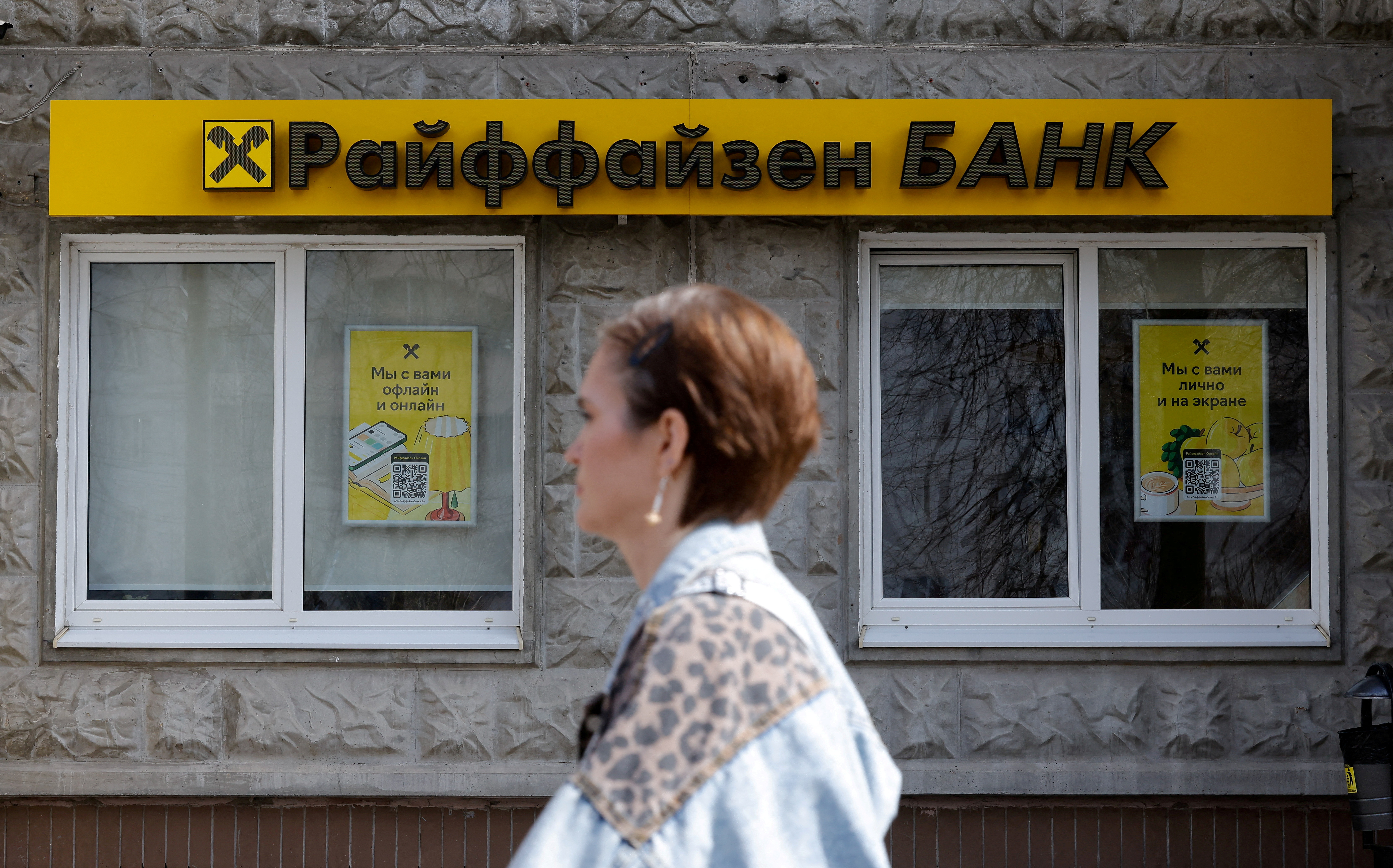 FILE PHOTO: A pedestrian walks past a branch of Raiffeisen Bank in Moscow, Russia, April 18, 2025. REUTERS/Maxim Shemetov/File Photo