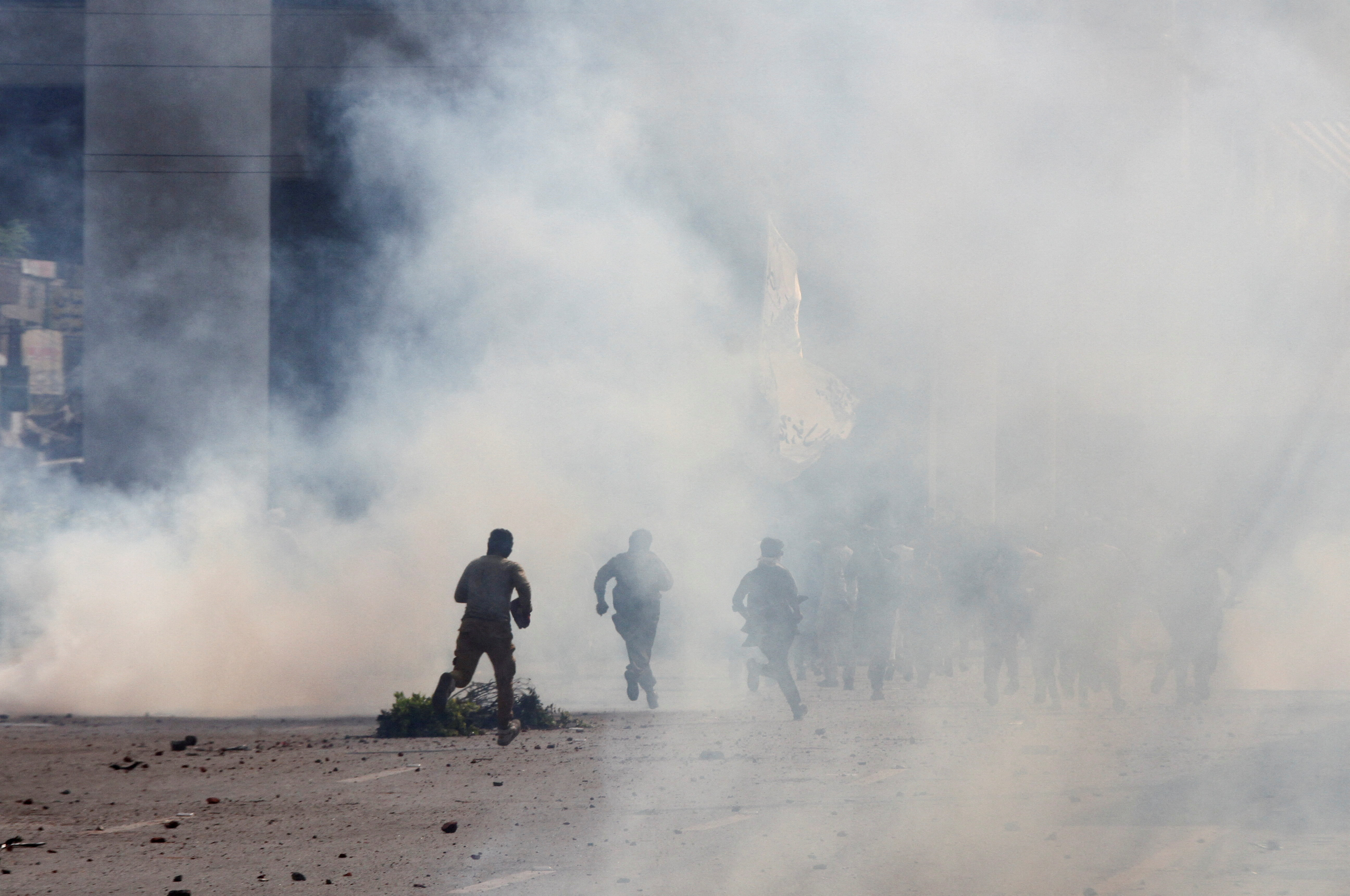 Police officers and supporters of Tehreek-e-Labbaik Pakistan (TLP) run amid tear gas fired by police during a solidarity march for Gaza in Lahore, Pakistan, October 10, 2025. REUTERS/Mohsin Raza TPX IMAGES OF THE DAY