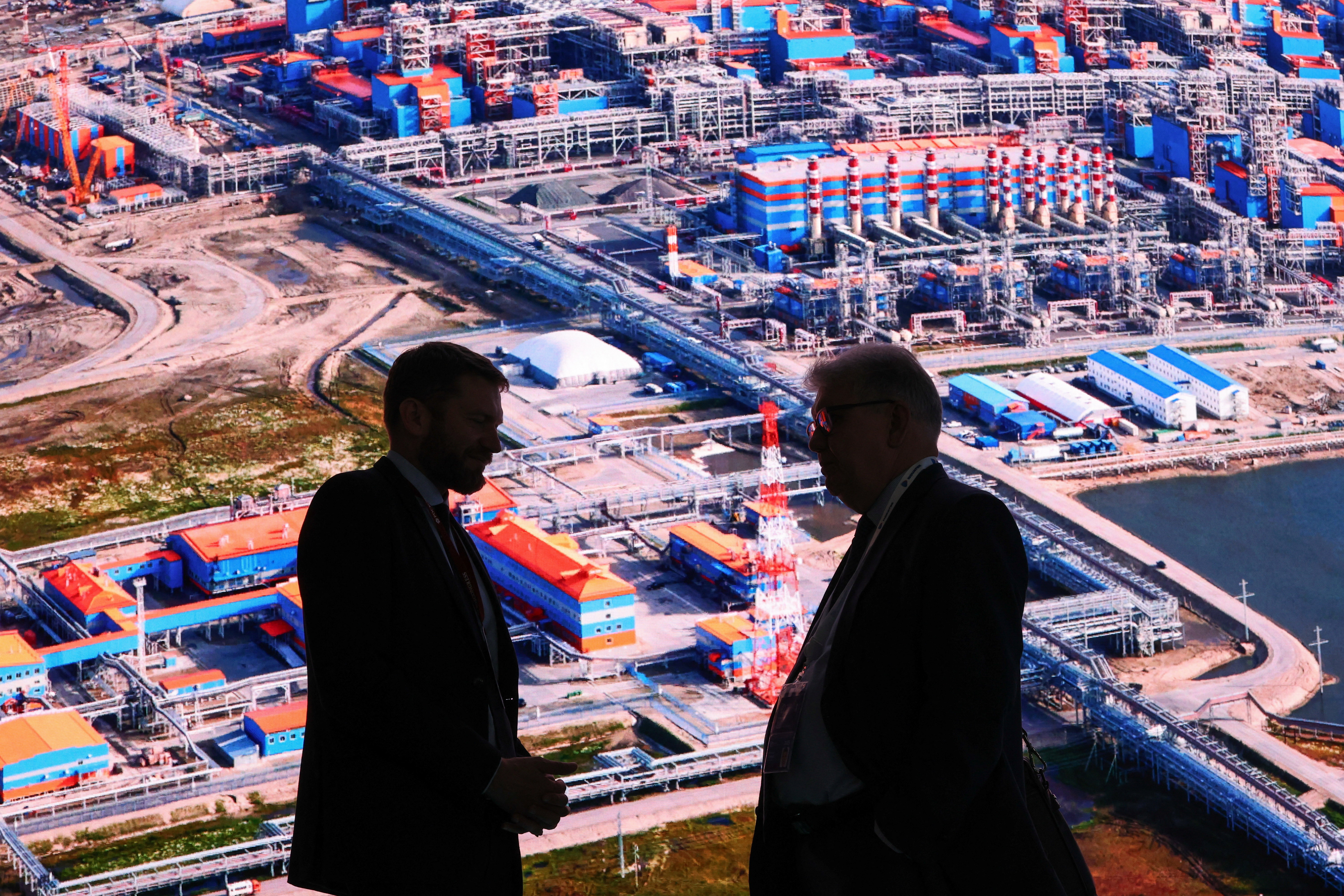 Participants speak in front of an exhibition stand of Russia's LNG producer Novatek.