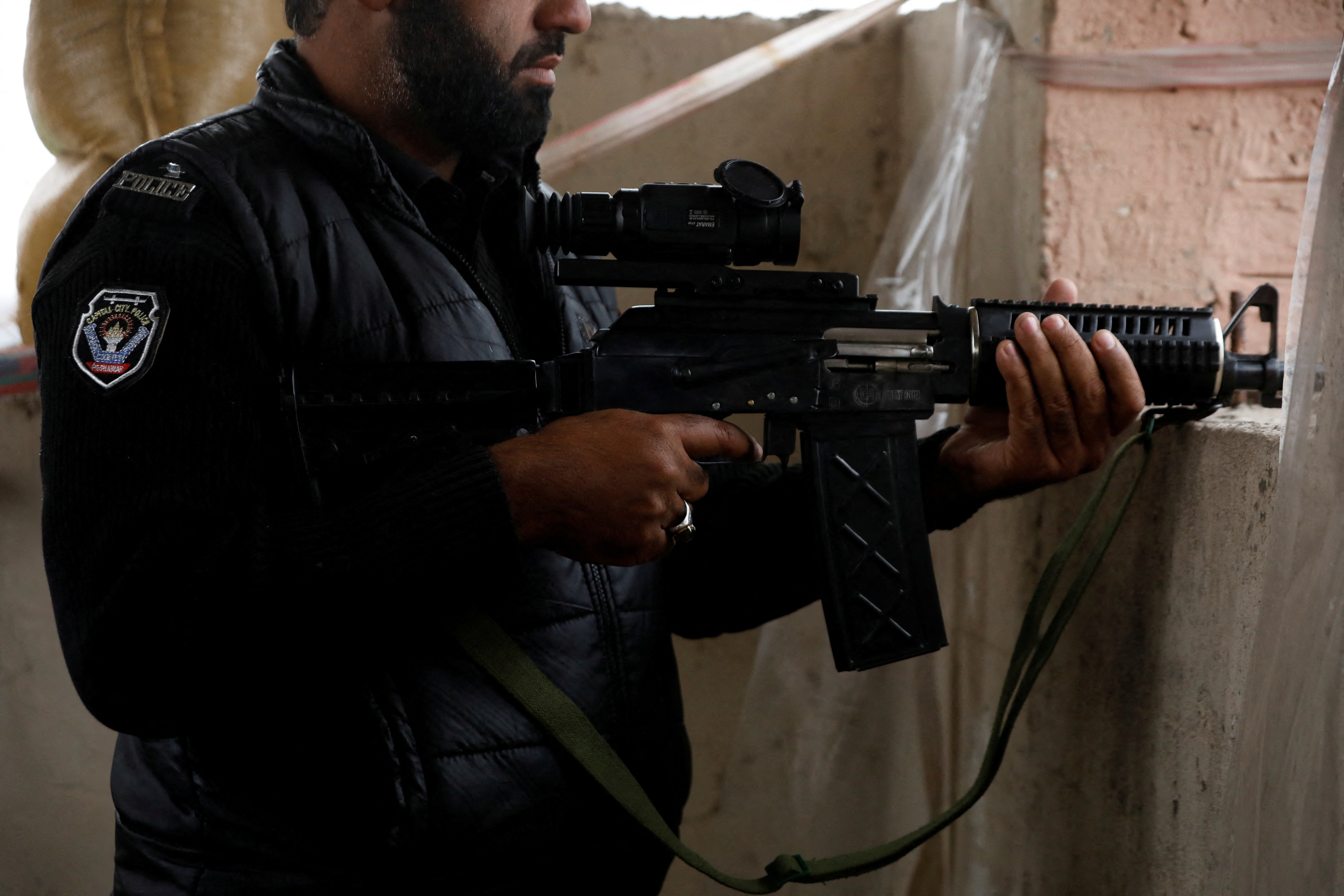 FILE PHOTO: A police officer holds a machine-gun with thermal binoculars attached to it, on the rooftop of Sangu's outpost, in the outskirts of Peshawar, Pakistan, February 9, 2023. REUTERS/Fayaz Aziz/File Photo