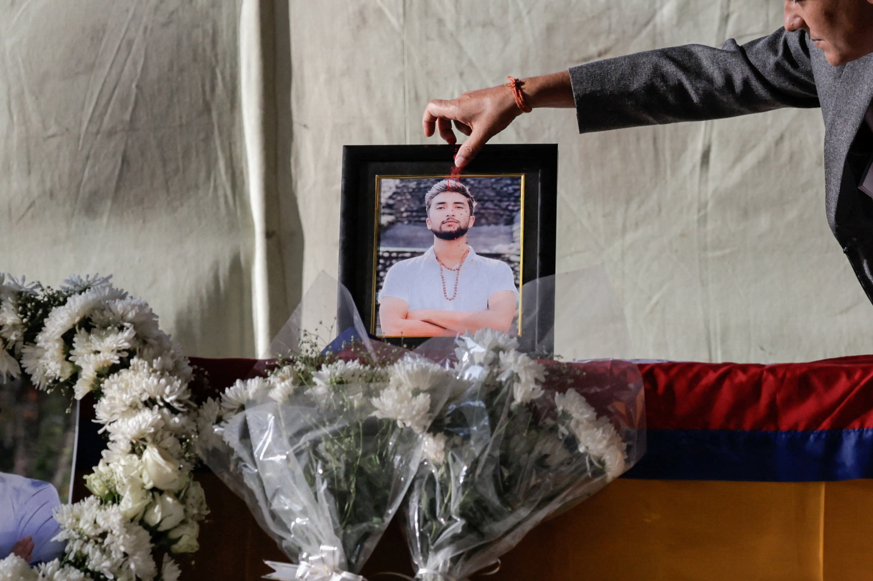 Nepalese Home Minister Om Prakash Aryal places a tika on a portrait on top of the coffin of Bipin Joshi, a Nepalese citizen who was kidnapped alive during the deadly October 7, 2023, attack on Israel by Hamas and died in captivity, after his body was brought back to Nepal, at Tribhuvan International Airport in Kathmandu, Nepal, October 20, 2025. [Navesh Chitrakar/Reuters]