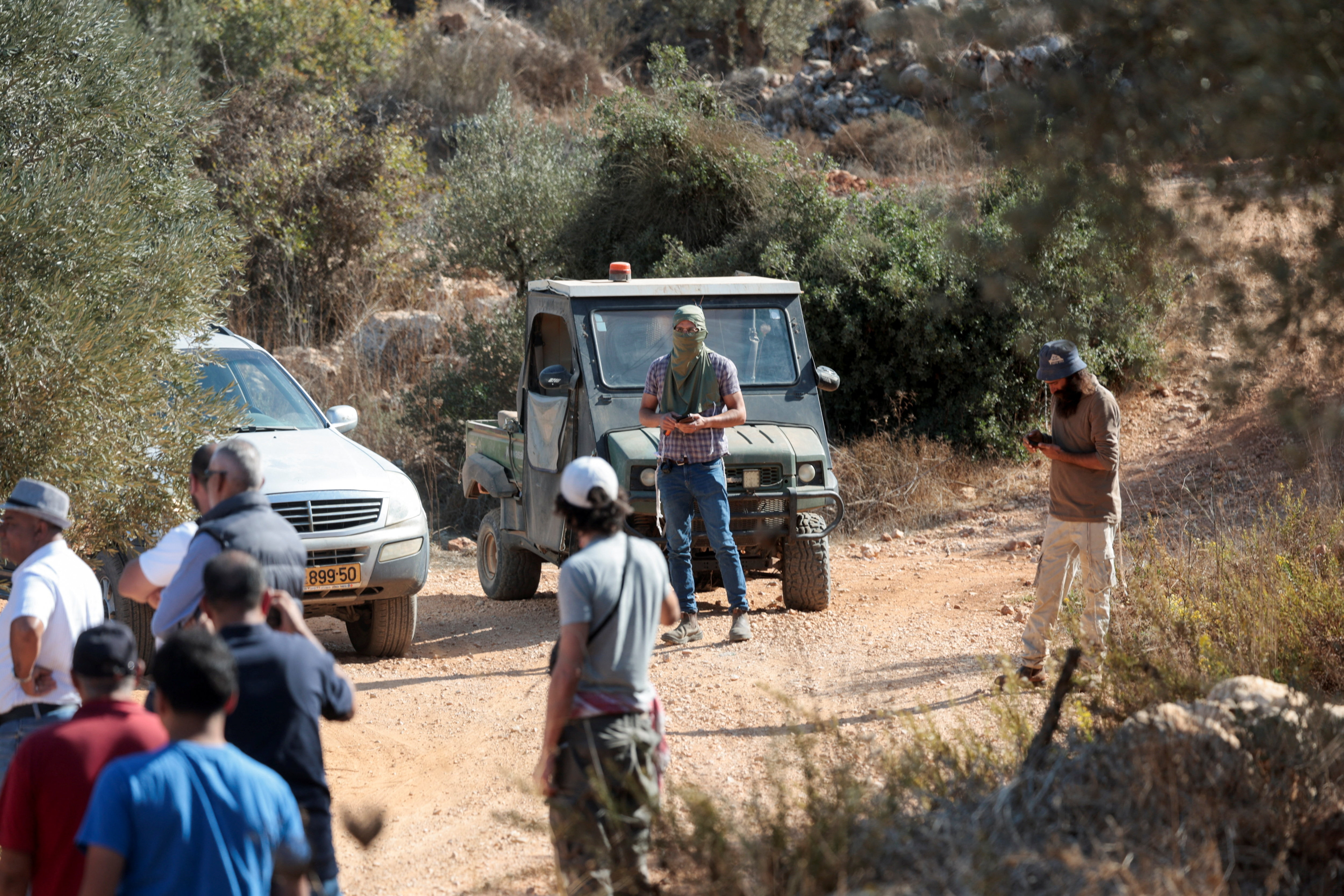Israeli settlers stand next to vehicles as they attempt to stop foreign activists and Palestinians from picking olives during harvest season in the village of Turmusaya near Ramallah, in the Israeli-occupied West Bank, October 28, 2025. REUTERS/Mohammed Torokman