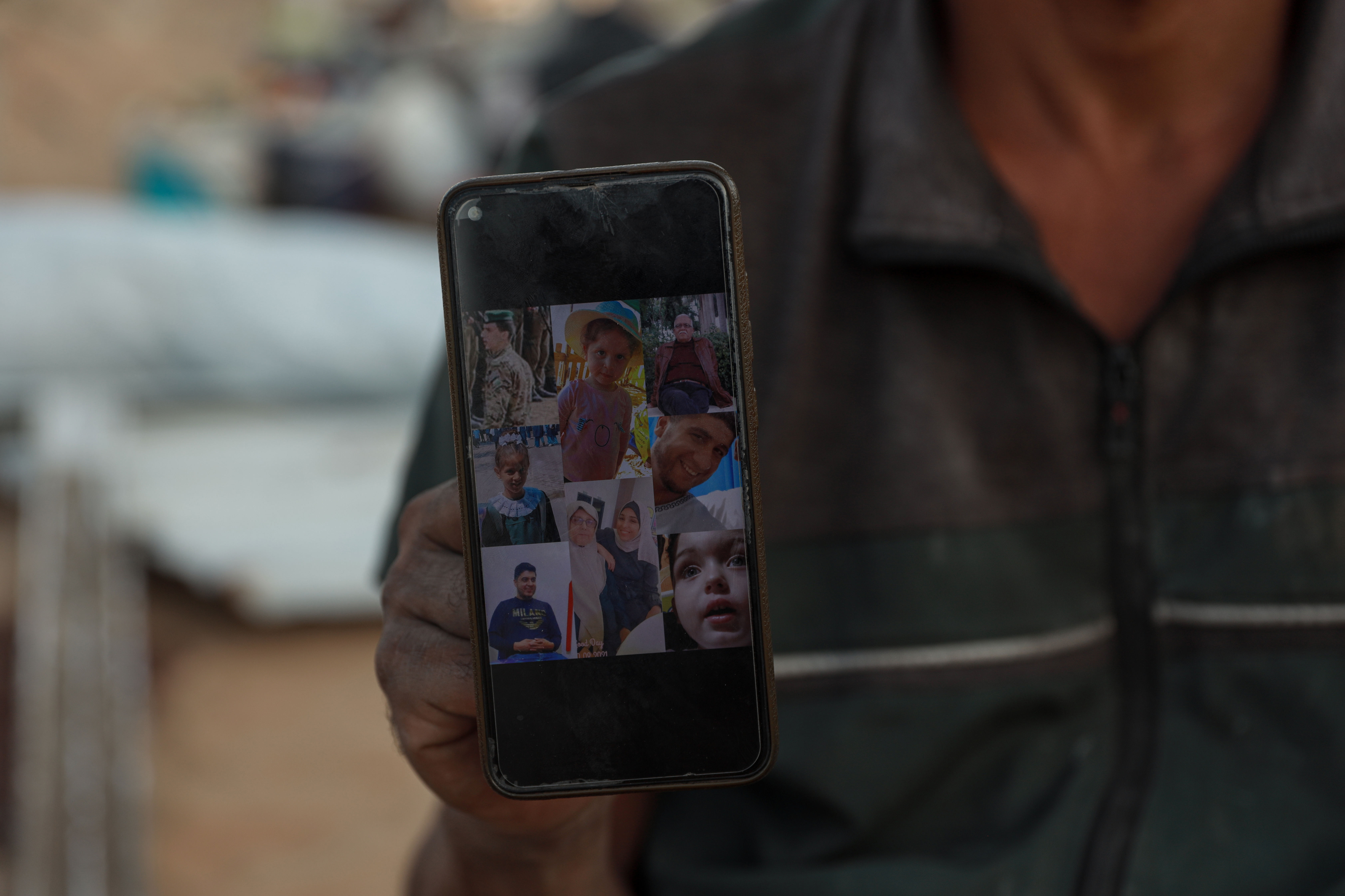 A man holds up a phone displaying a collage of family members
