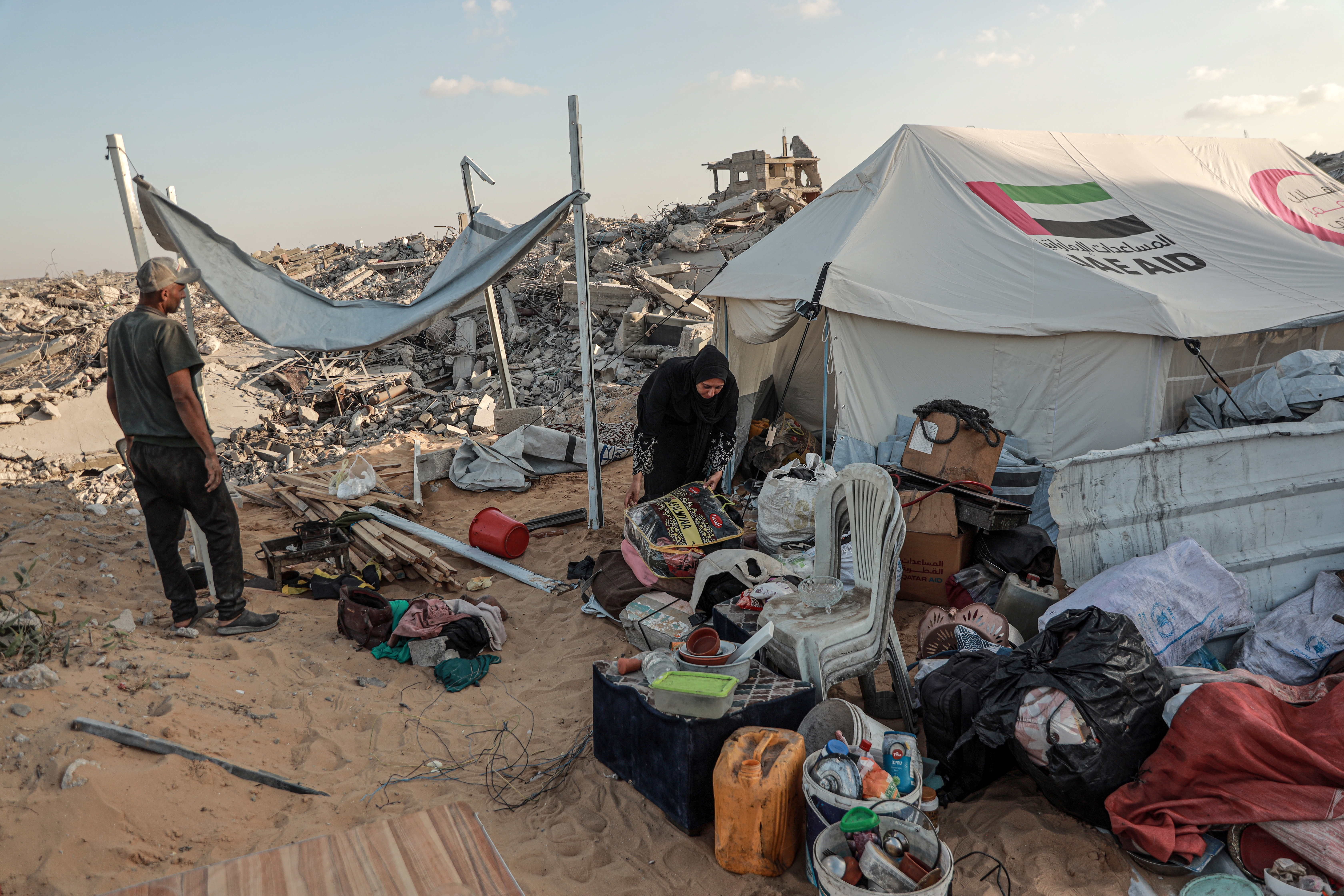 A woman sorts through her belongings next to a tent
