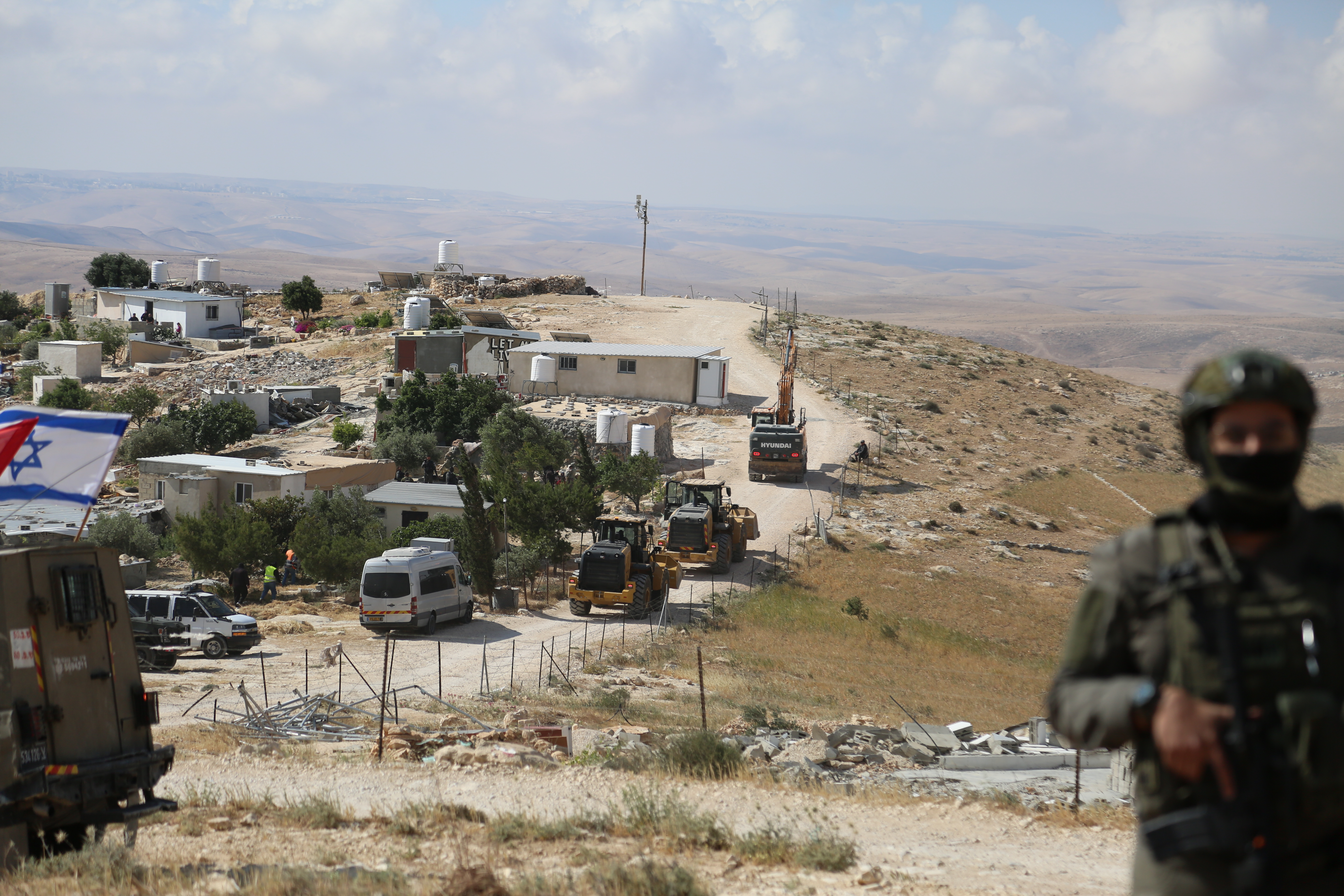 An Israeli soldier in the foreground with bulldozers in the background