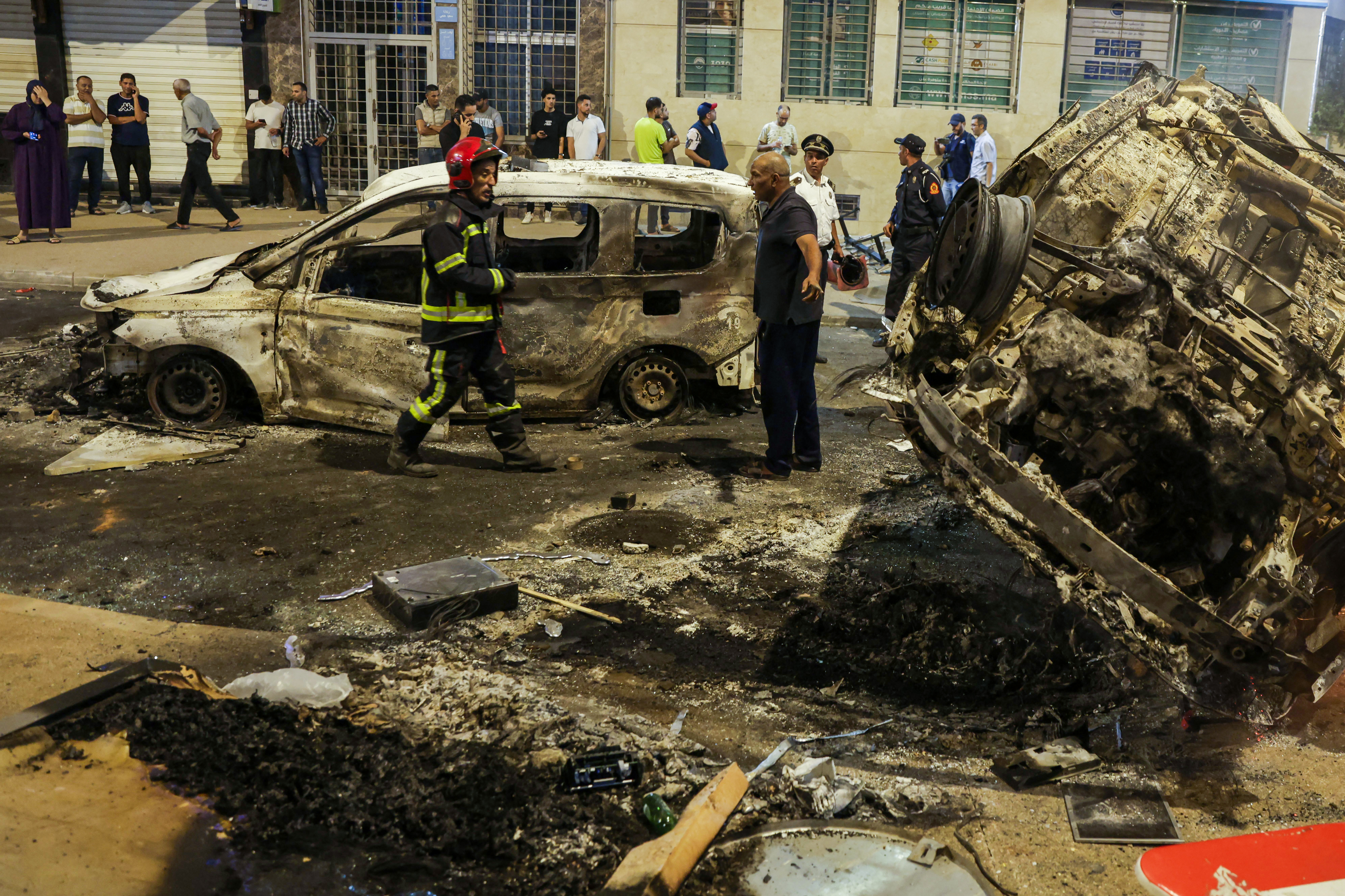 People look at burnt-out vehicles set on fire during a youth-led demonstration demanding reforms in the healthcare and education sectors in Morocco [Abdel Majid BZIOUAT/AFP]