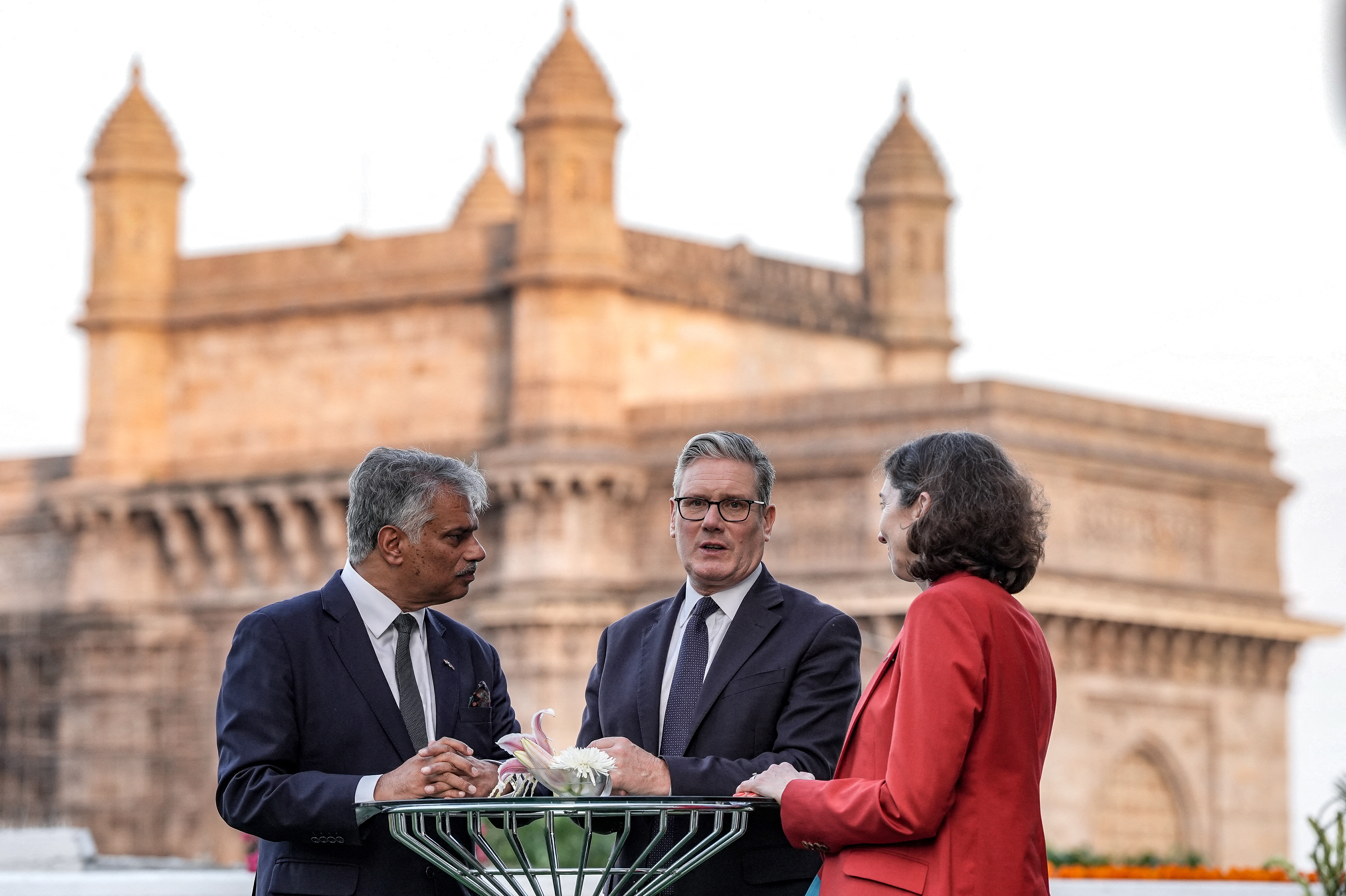UK Prime Minister Keir Starmer, centre, speaks to Harjinder Kang, left, the UK Trade Commissioner for South Asia, and UK High Commissioner to India, Lindy Cameron, in front of the Gateway of India in Mumbai