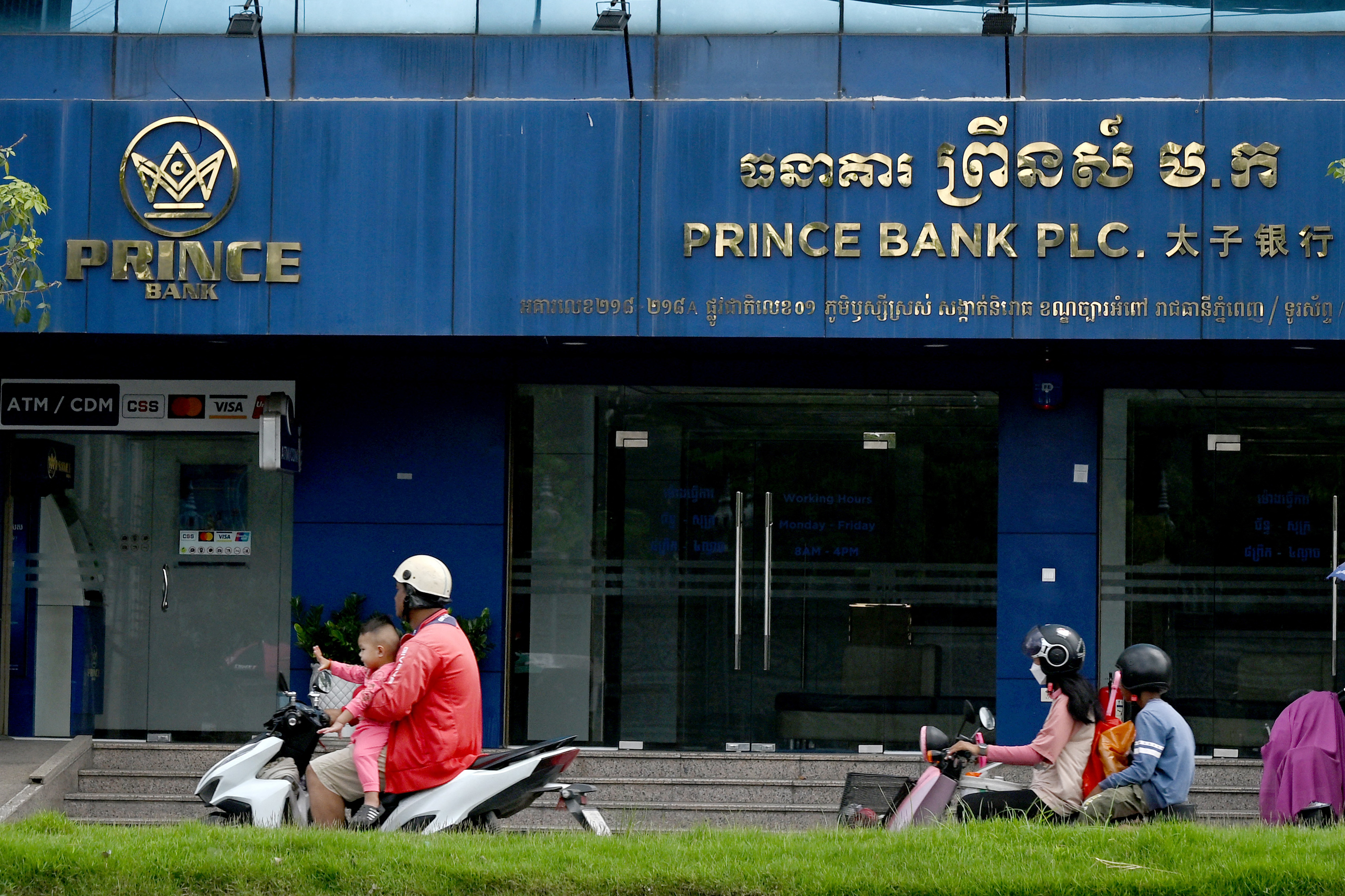 Motorists ride past a branch of the Prince Bank in Phnom Penh, Cambodia.