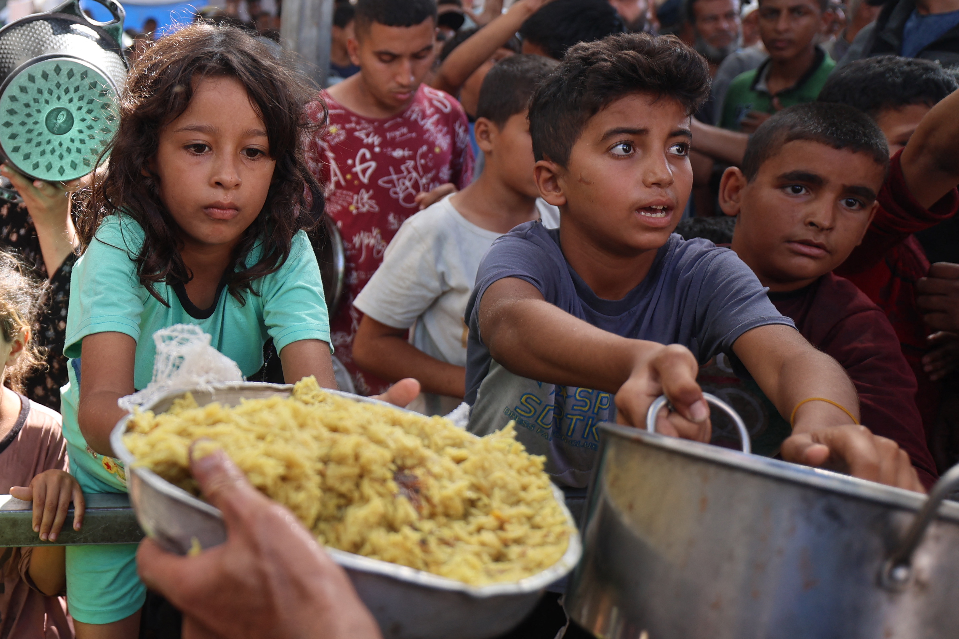 Palestinian children gather to receive food portions from a charity kitchen in the Nuseirat refugee camp, located in the central Gaza Strip, on October 21, 2025 [File: Eyad Baba/AFP]