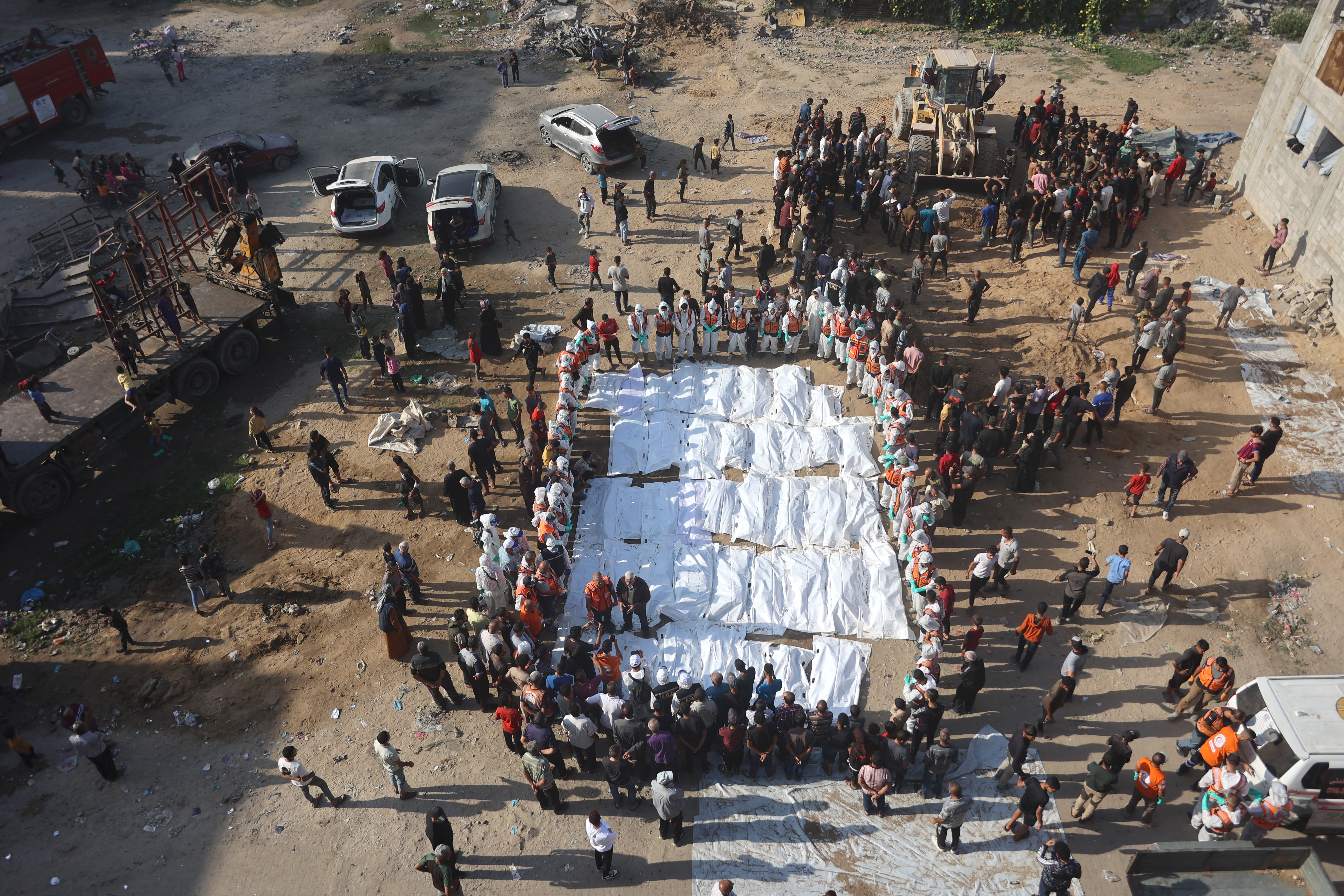 Civil Defense members, in cooperation with the Palestinian Shahebar family, lay out body bags containing the remains of members of the Shahebar family, who were buried in temporary graves and brought to the Sheikh Shaaban Cemetery, in Gaza City