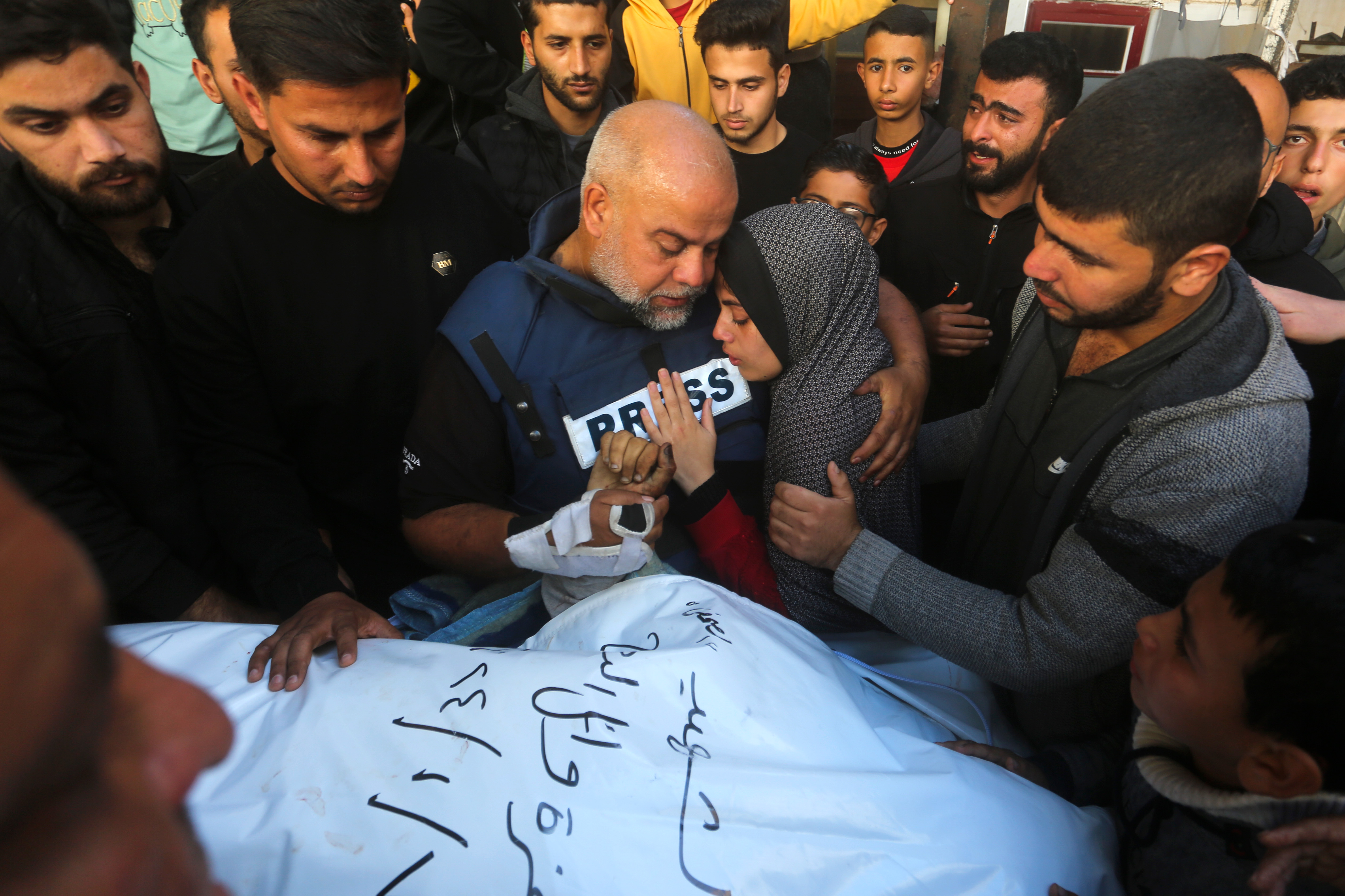 Al Jazeera journalist Wael Dahdouh holds the hand of his son Hamza, who also worked for Al Jazeera and who was killed in an Israeli airstrike in Rafah, Gaza Strip, Sunday, Jan. 7, 2024. Dahdouh lost his wife, two other children and a grandson earlier in the war and was nearly killed himself. [Hatem Ali/AP Photo]