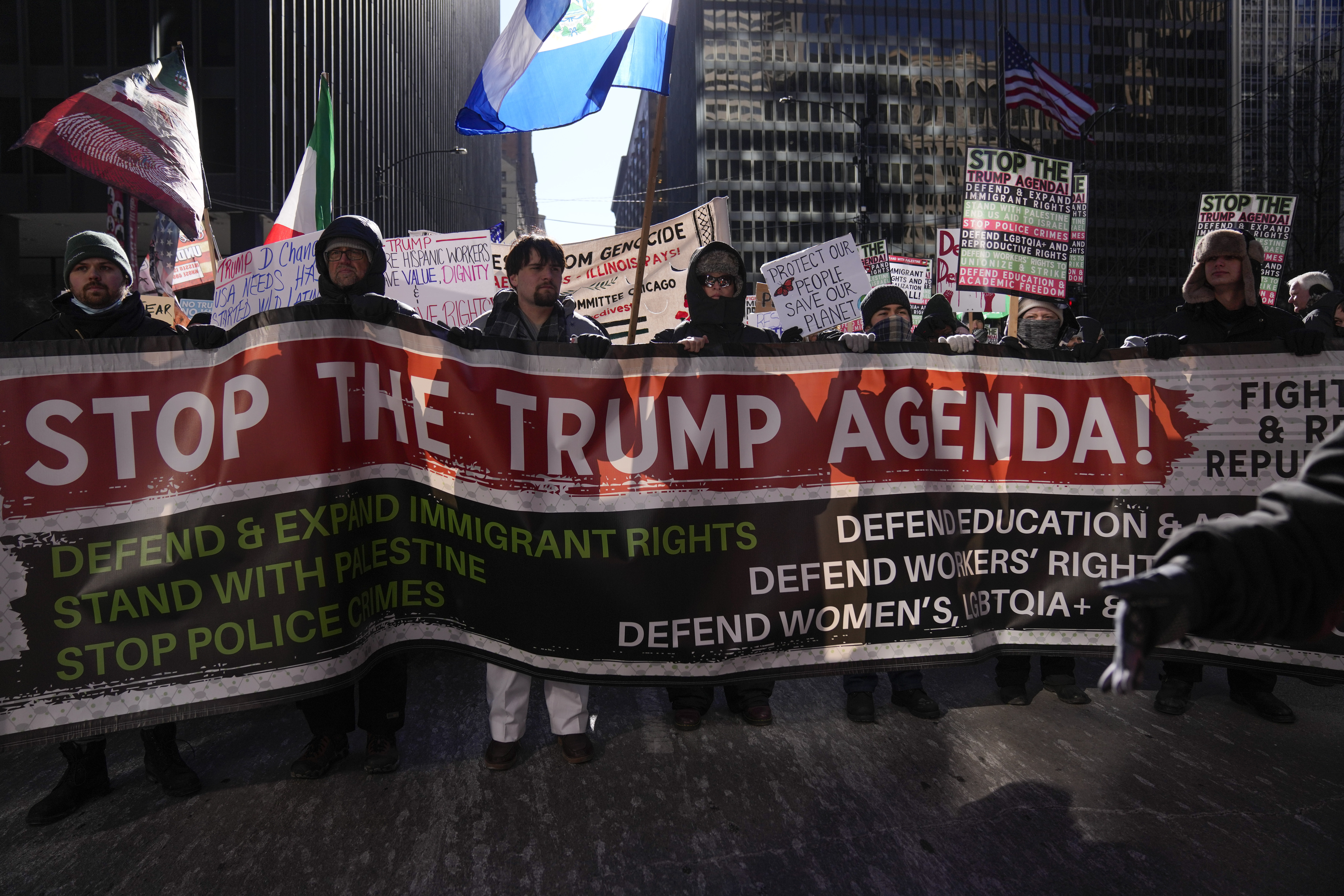 Protesters hold a banner that reads "Stop the Trump Agenda."