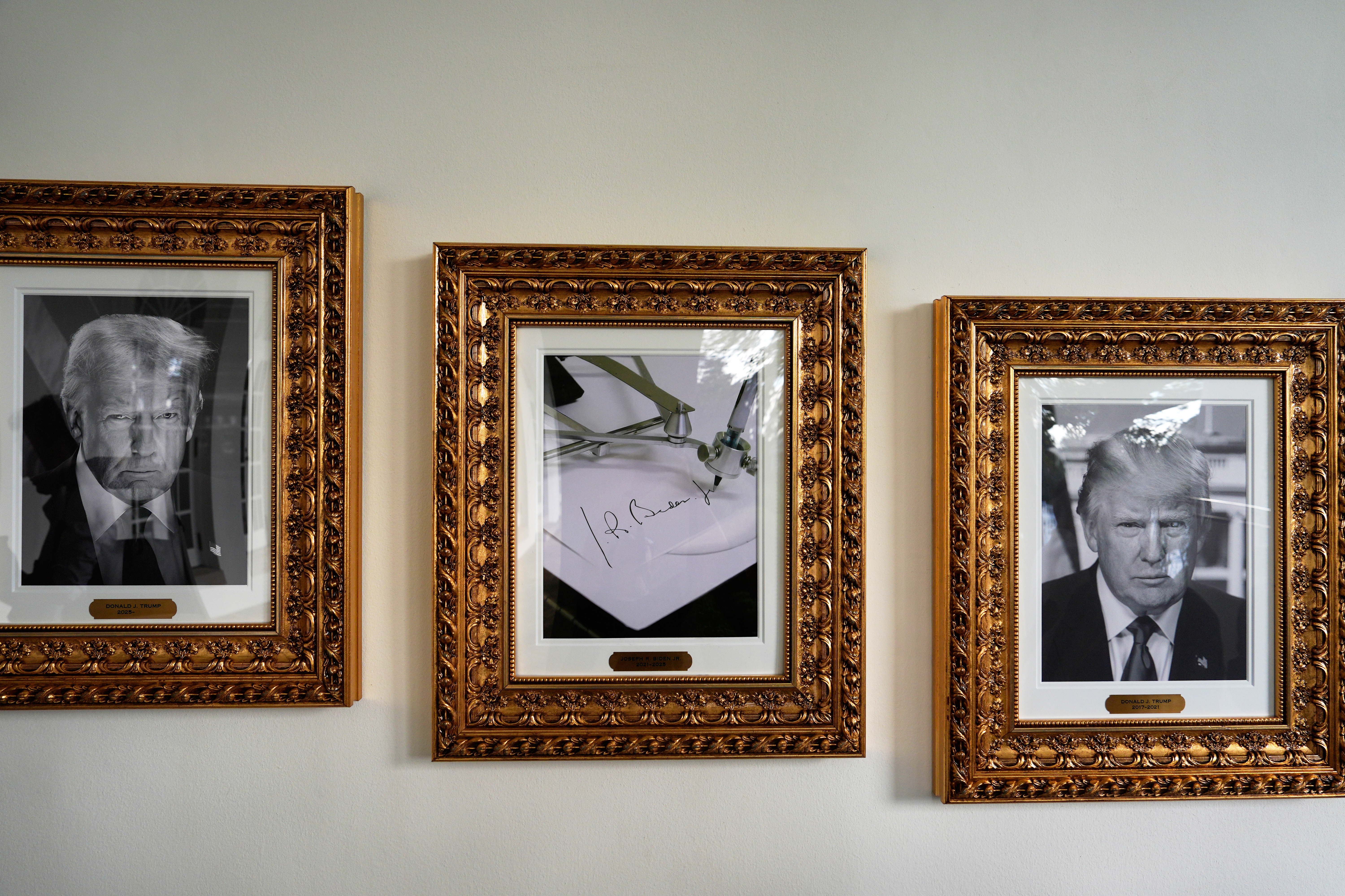 Trump displays a photo of Joe Biden as an autopen between his own portraits.