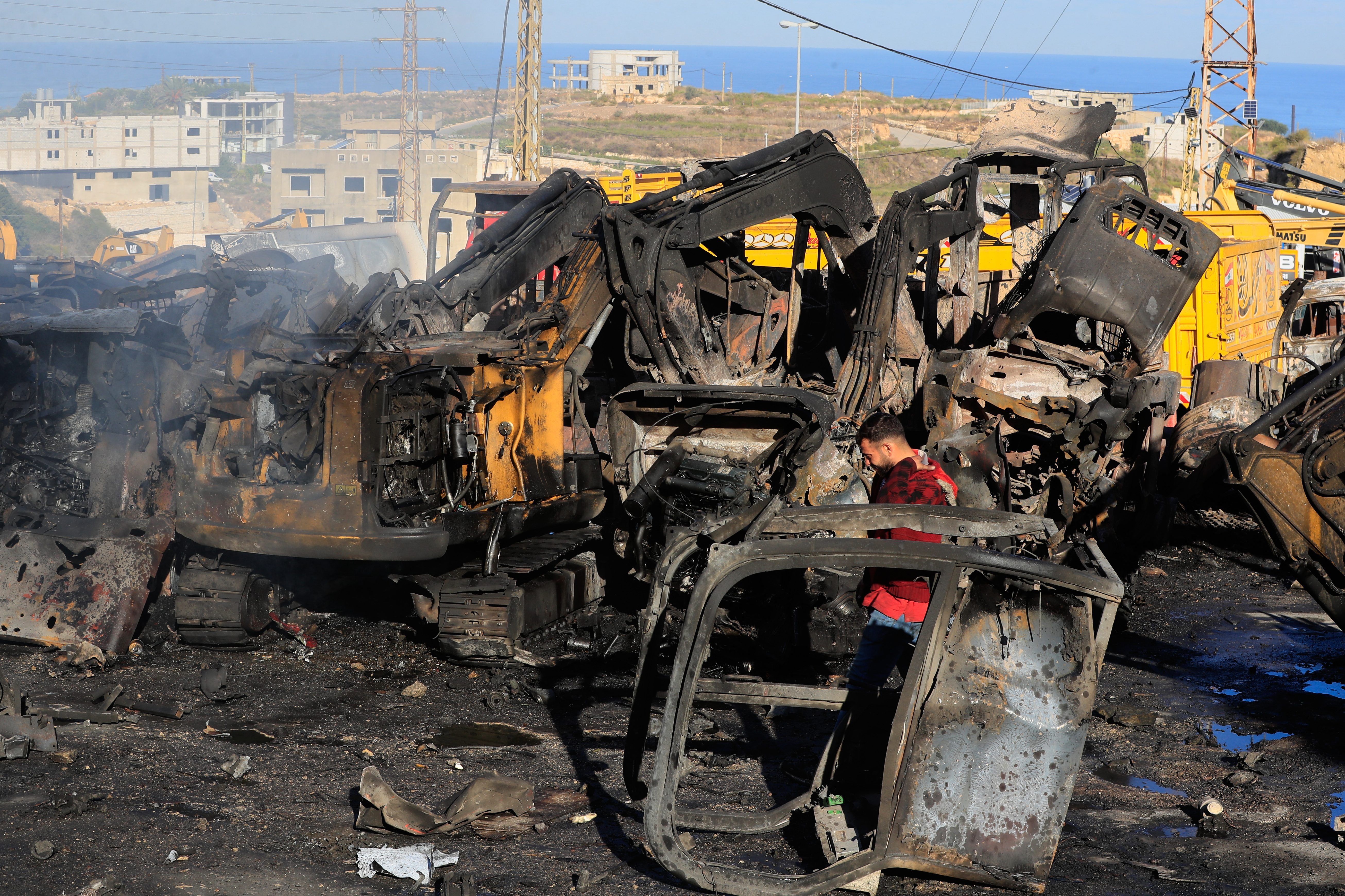 A man walks at a site that sold heavy machinery, where a large number of vehicles were destroyed in Israeli airstrikes, in the southern village of Msayleh, Lebanon, Saturday, Oct. 11, 2025. (AP Photo/Mohammed Zaatari)