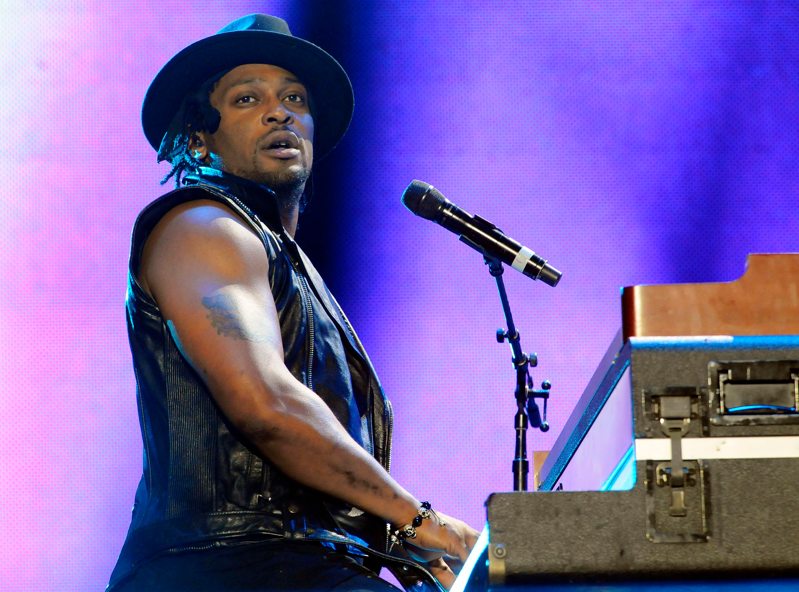 D'Angelo performs at the 2012 Essence Festival, singing into a microphone and playing the piano.