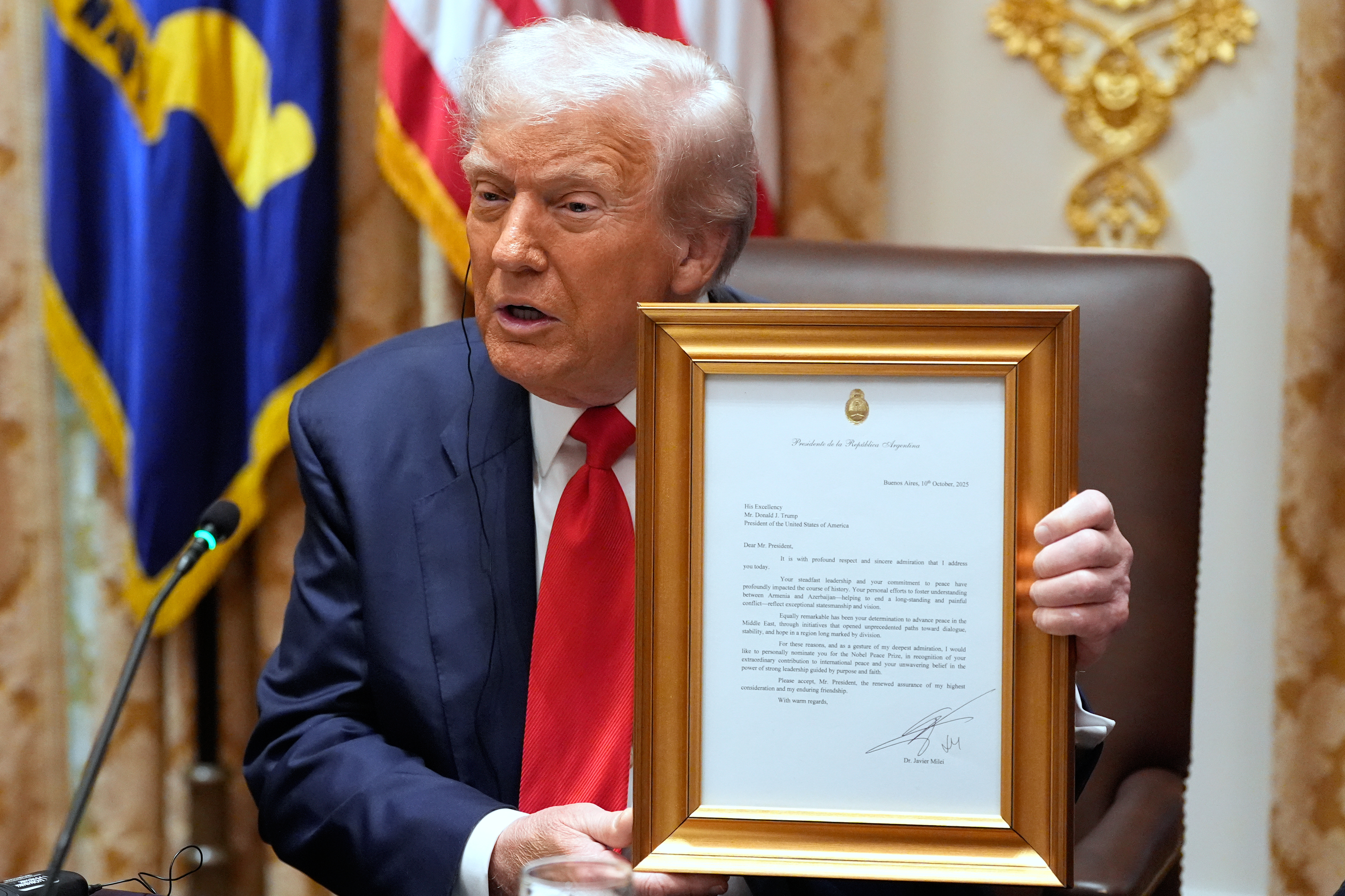 Donald Trump holds up a framed letter from Javier Milei