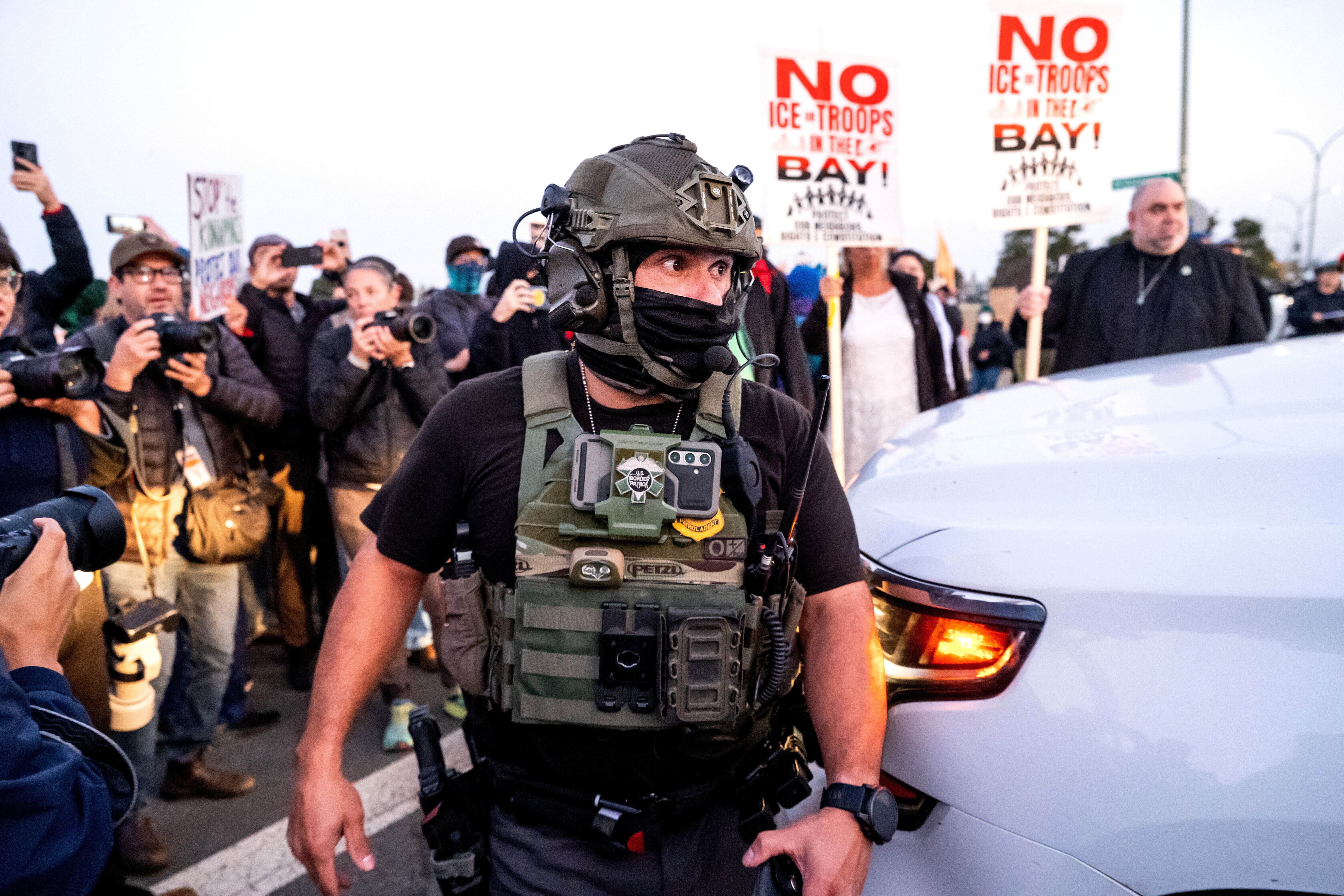 A US Border Patrol agent tries to clear protesters away from a car entering a Coast Guard facility