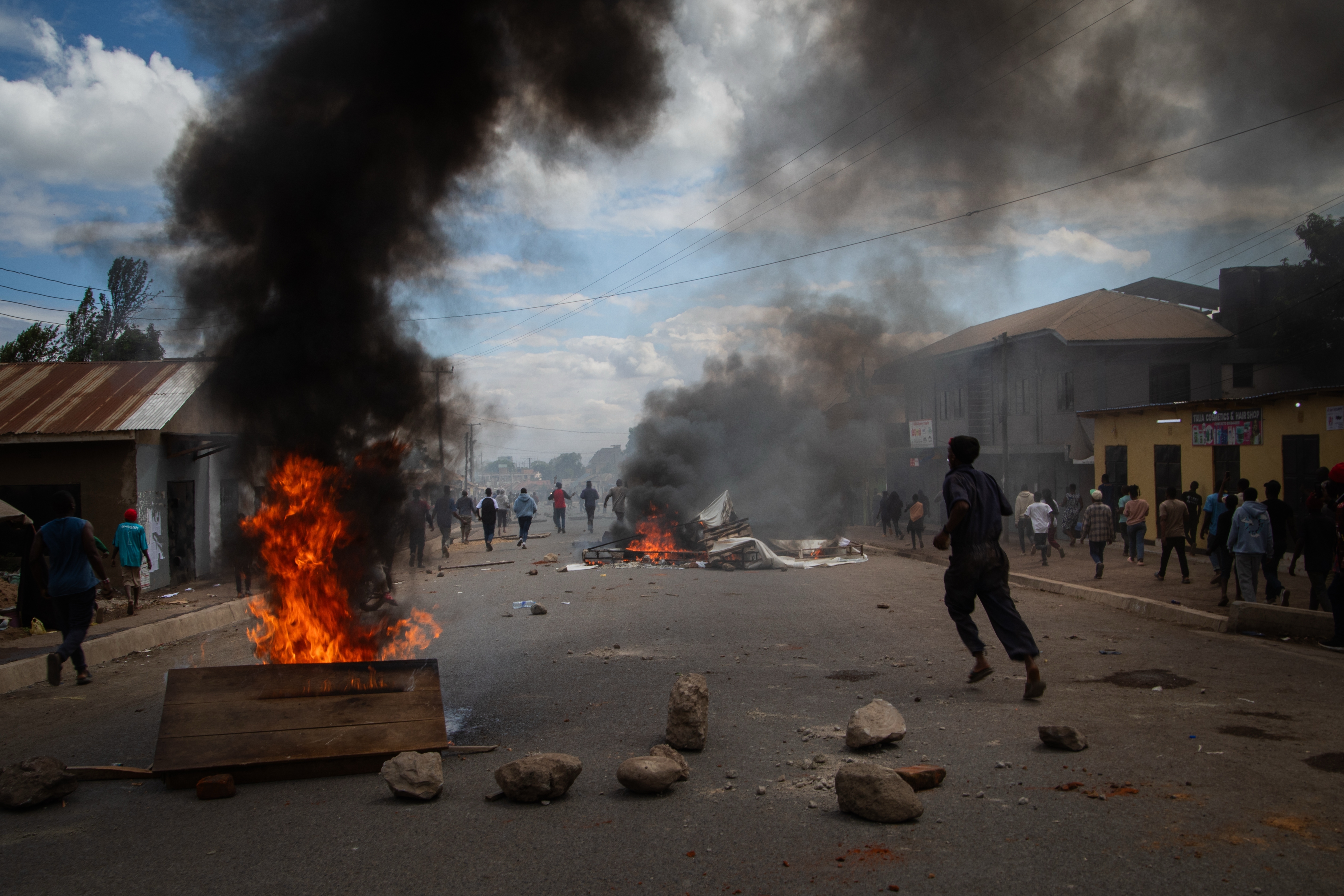 People protest in the streets as fires burn.