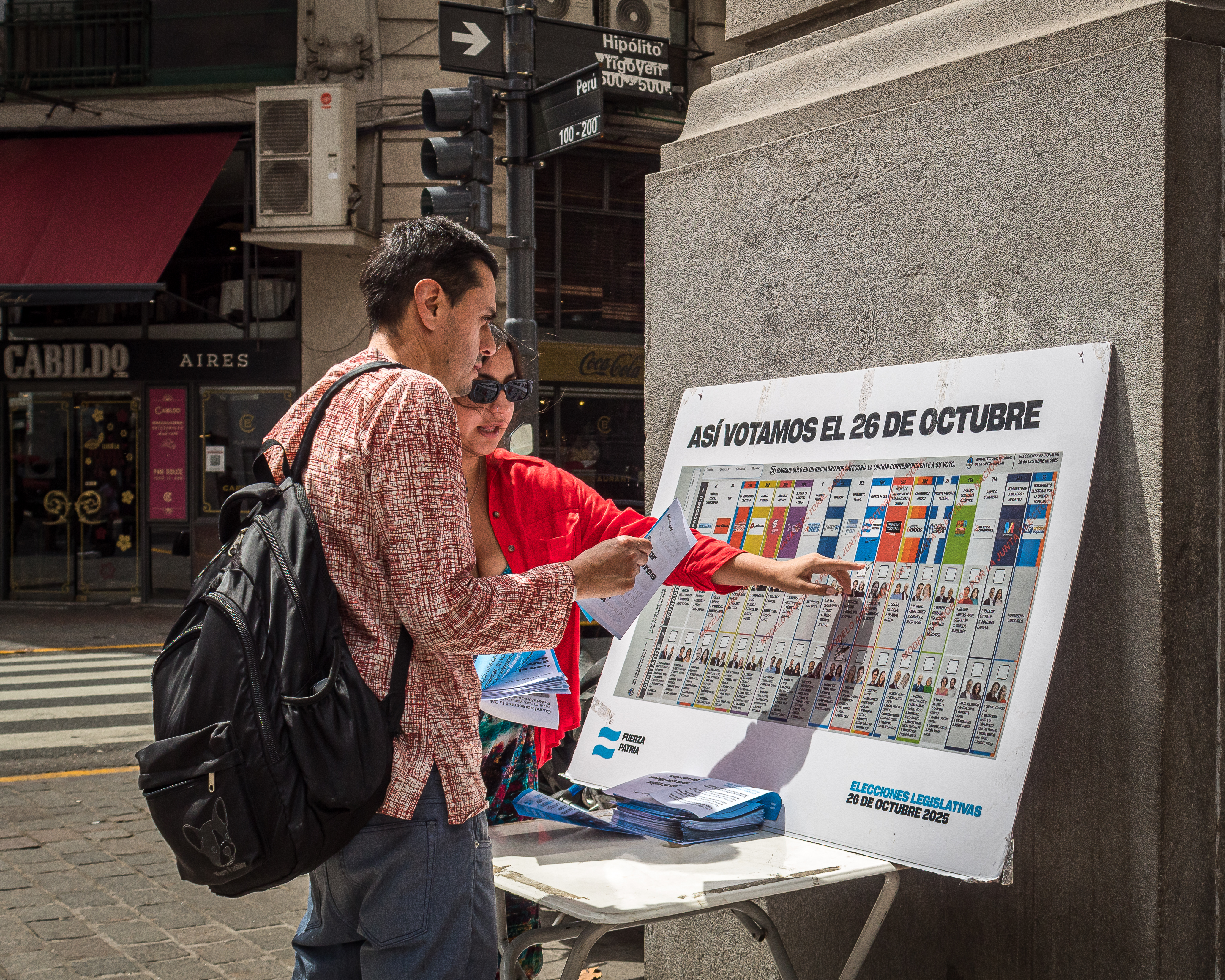 A passerby looks at a sign explaining the single-ballot voting system in Argentina