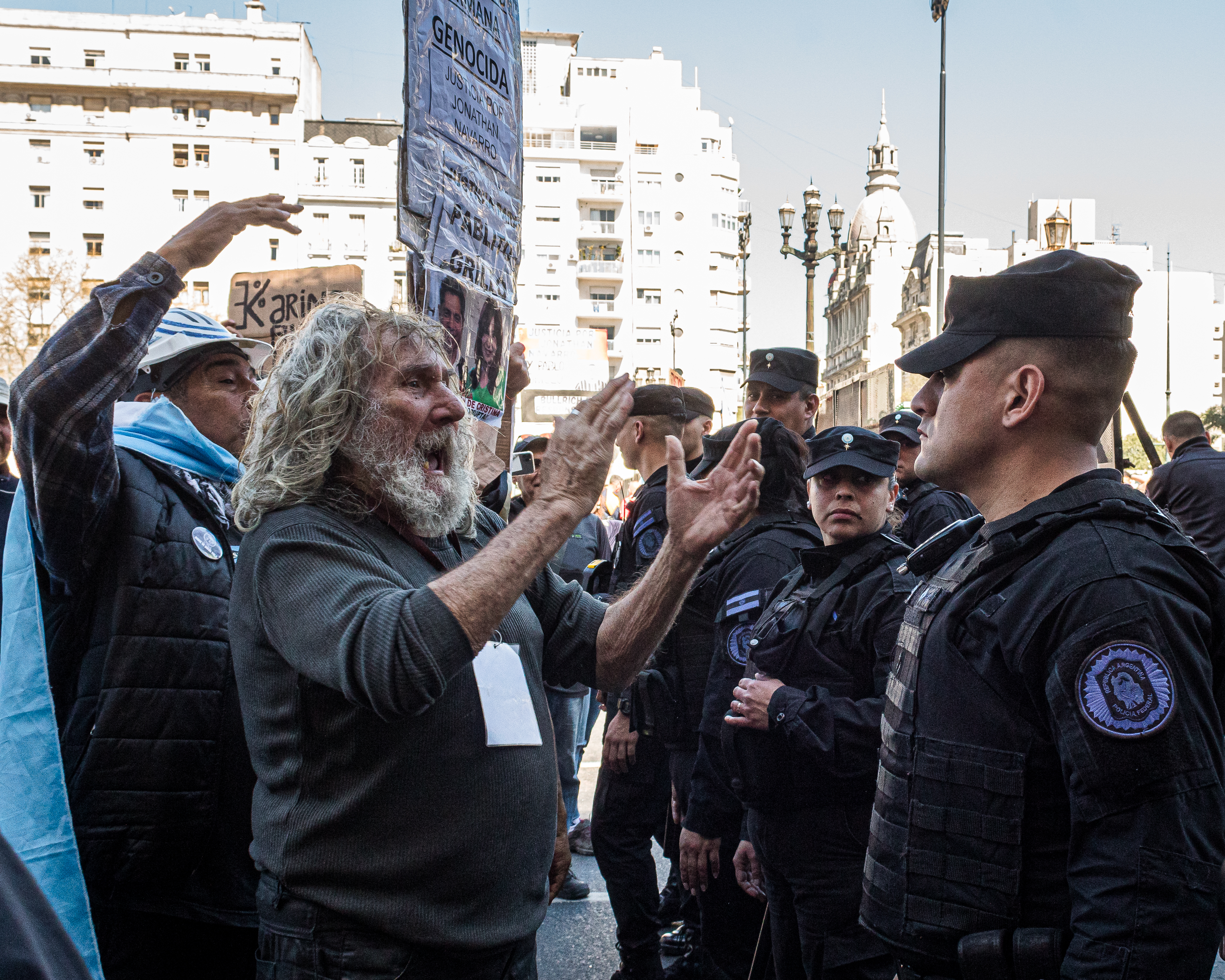 Elderly protesters yell in front of a line of police officers