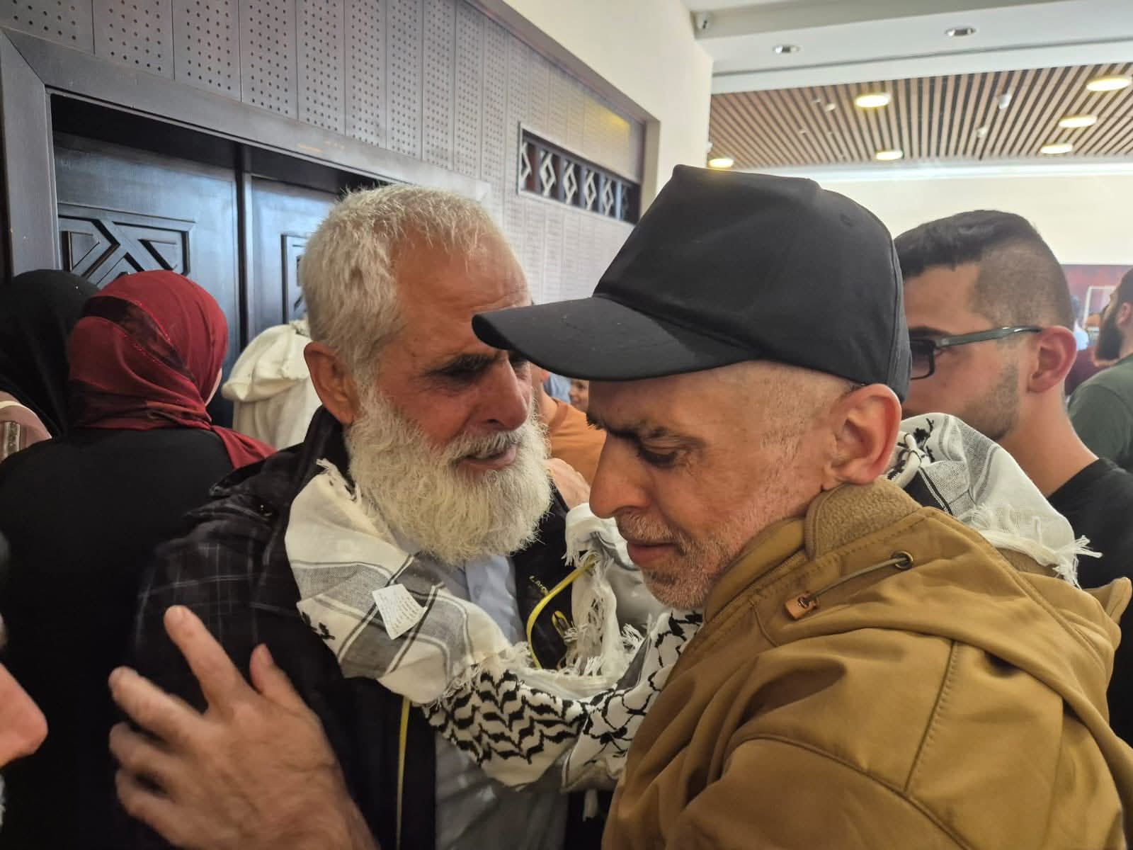 Bassam is bare-headed, with a soft white beard. Hani wears a cap and looks emaciated after his time in Israeli prison