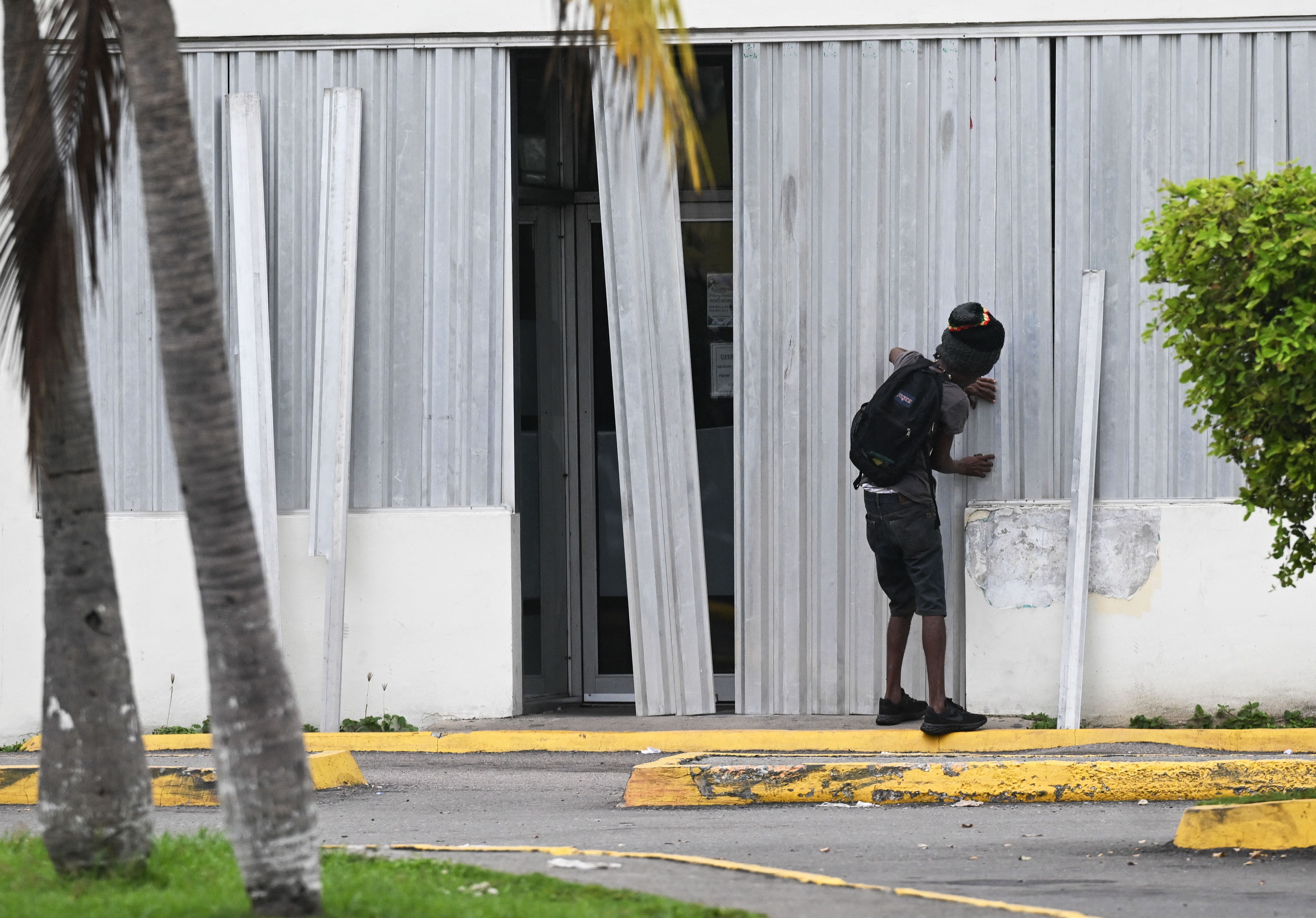 A man installs storm shutters at a business in preparation for the arrival of Hurricane Melissa in Portmore, St. Catherine parish, Jamaica, on October 25, 2025.