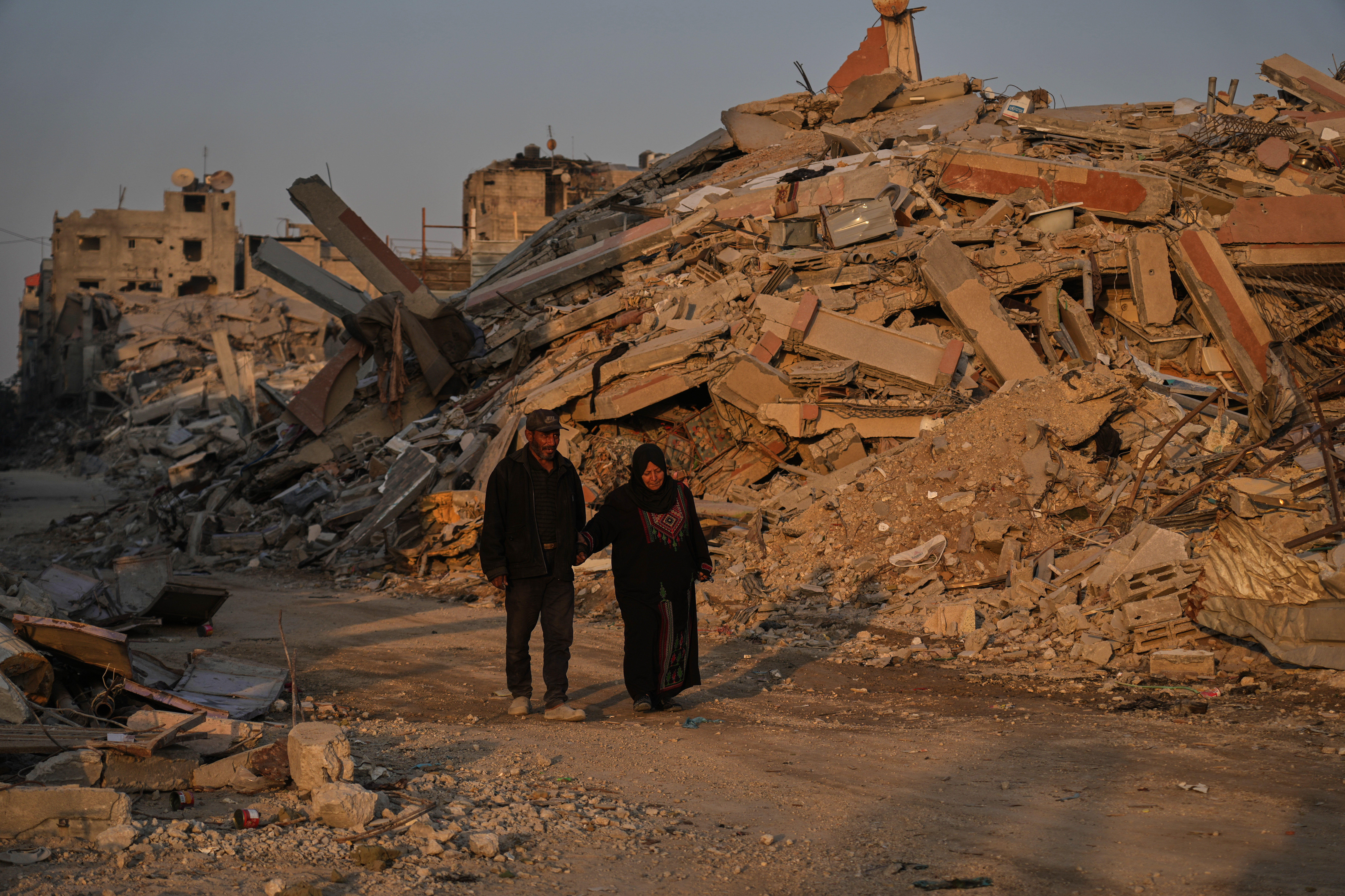 Palestinians walk trough the destruction caused by the Israeli air and ground offensive in Gaza City, Thursday, Oct. 23, 2025. (AP Photo/Abdel Kareem Hana)