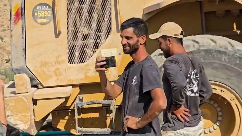 Israeli settler Yinon Levi smiles as construction workers illegally excavate in the occupied West Bank village of Umm al-Kheir. [Al Jazeera]