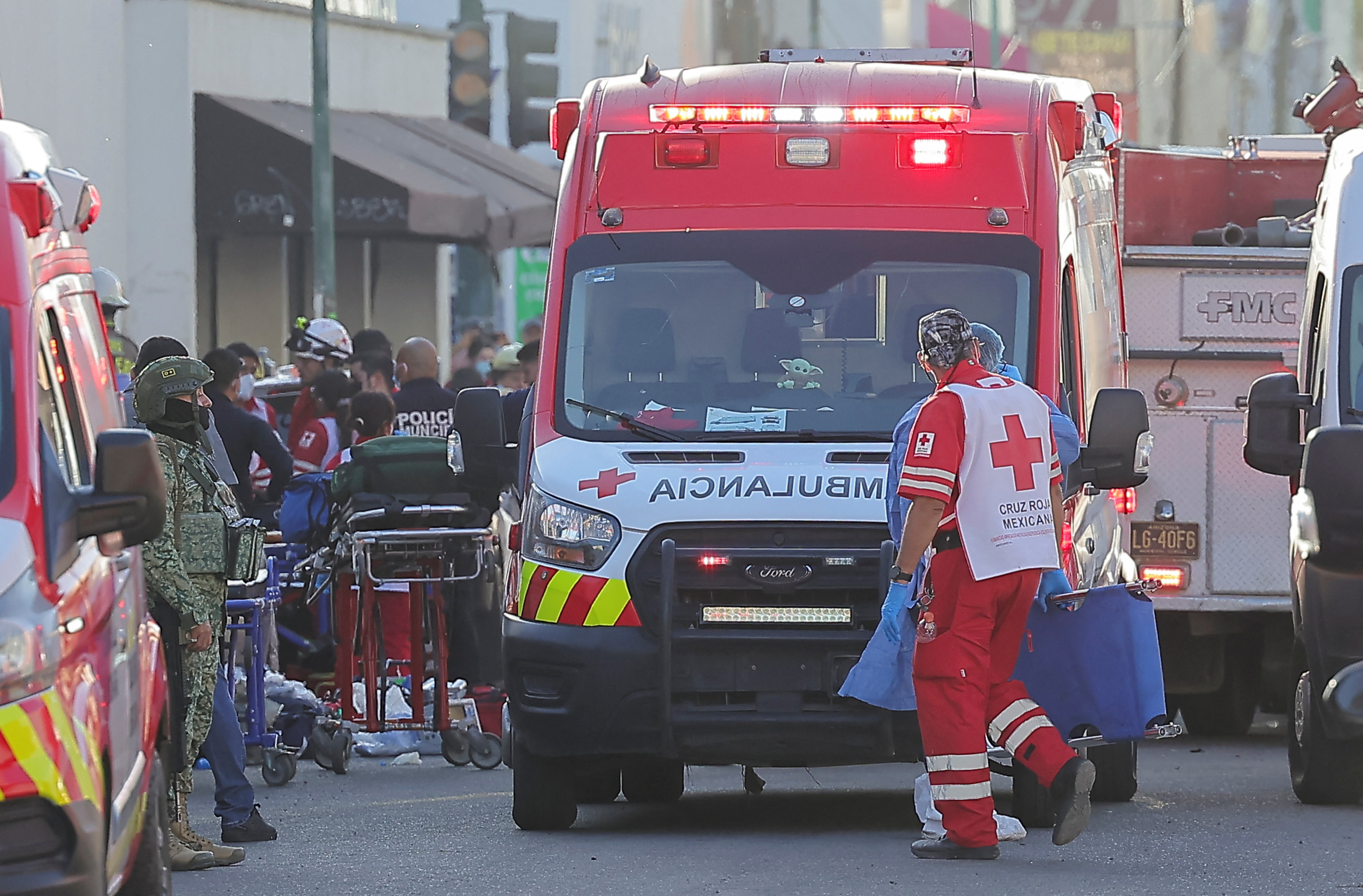 A medic stands near an ambulance outside a storefront.