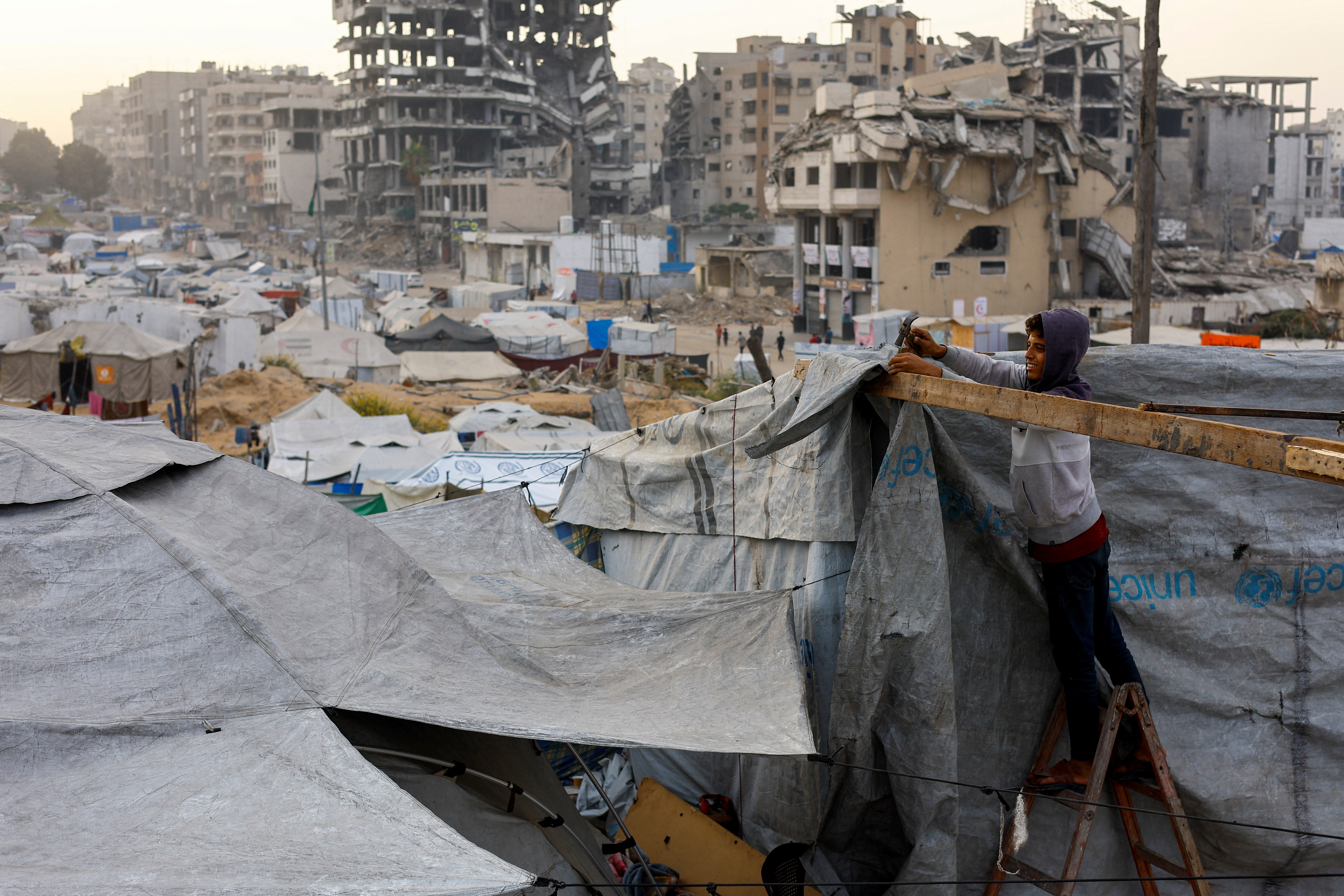 A displaced Palestinian fixes a tent in Gaza City
