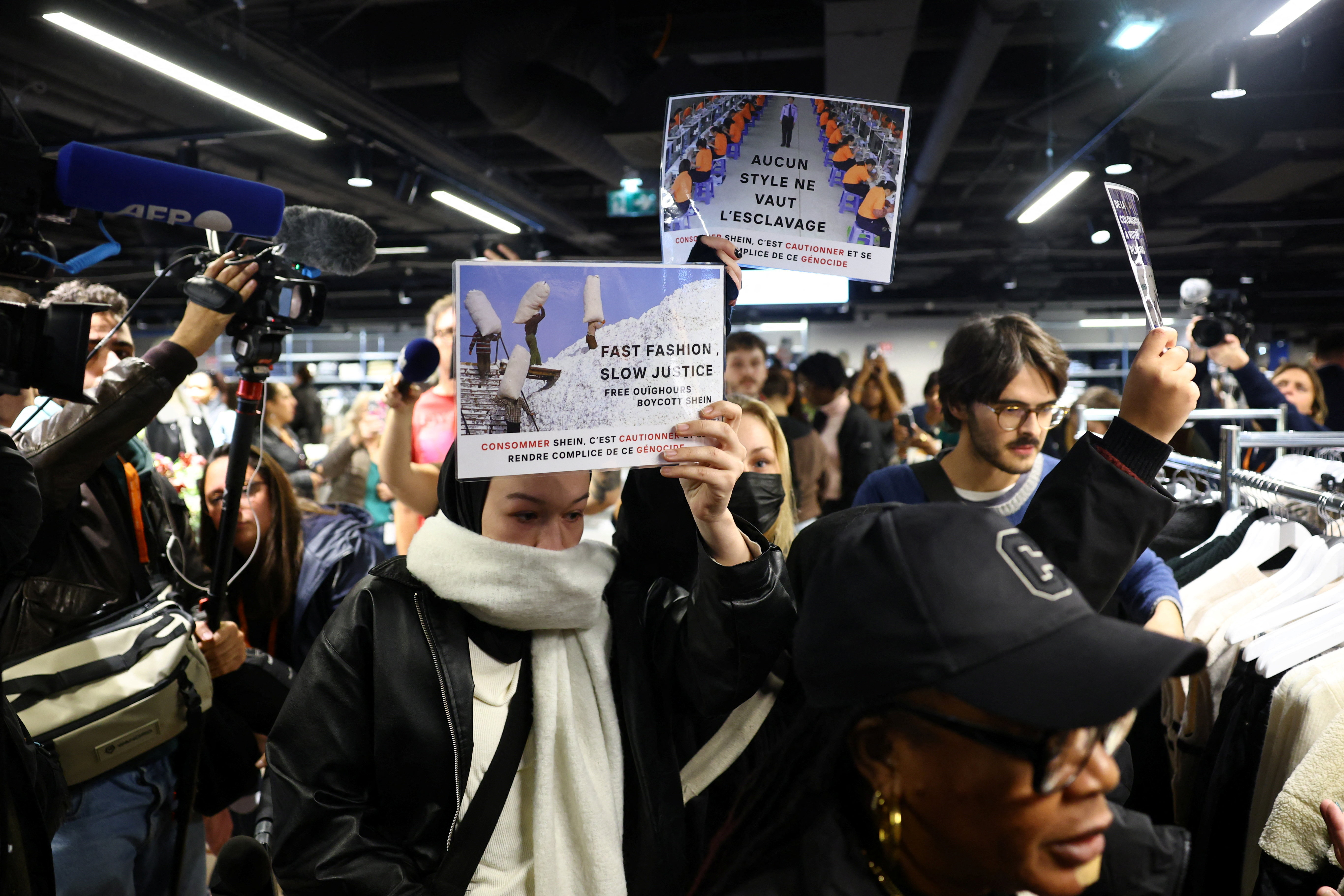 Protesters hold placards that read, 'Fast fashion, slow justice. Free Uighurs, boycott Shein. Buying Shein is condoning and becoming complicit in this genocide', during a protest inside the company's physical space, on November 5, 2025 [Sarah Meyssonnier/Reuters]