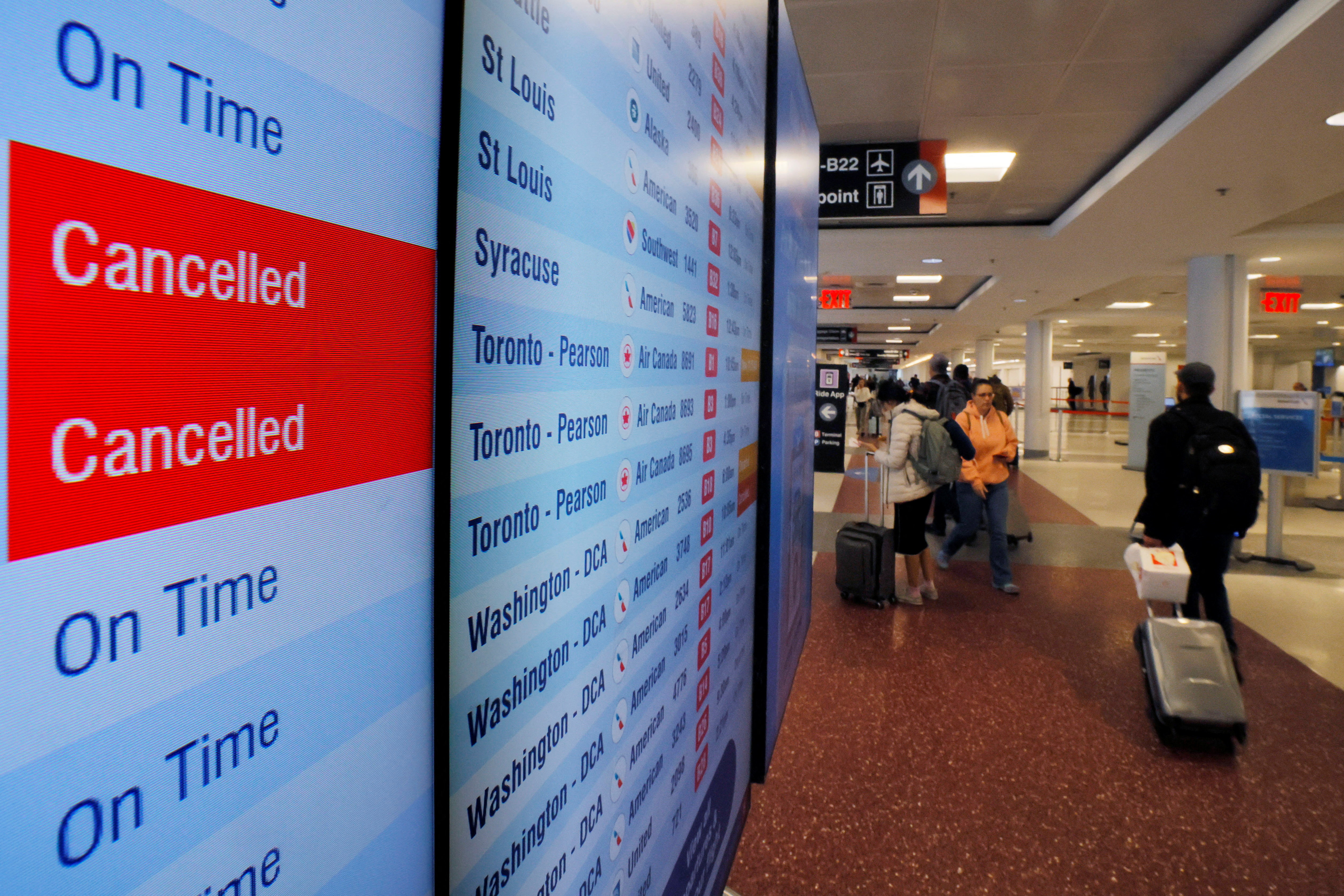 A board at an airport shows two cancelled American Airlines flights and three on time.