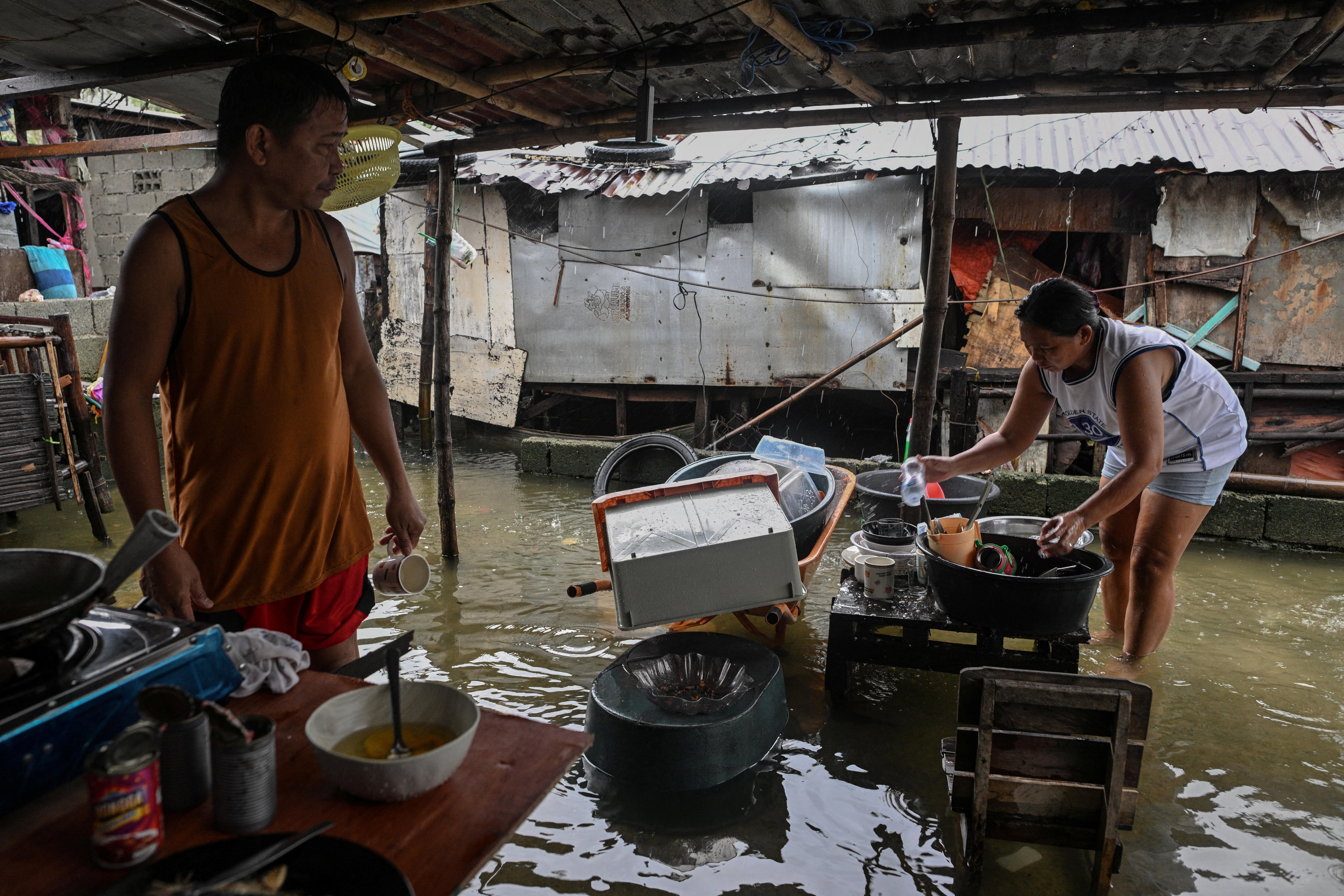 Evelyn Salvador, 49, washes the dishes outside her flooded house after Typhoon Fung-wong hit Dagupan City, Pangasinan, Philippines, November 10, 2025.