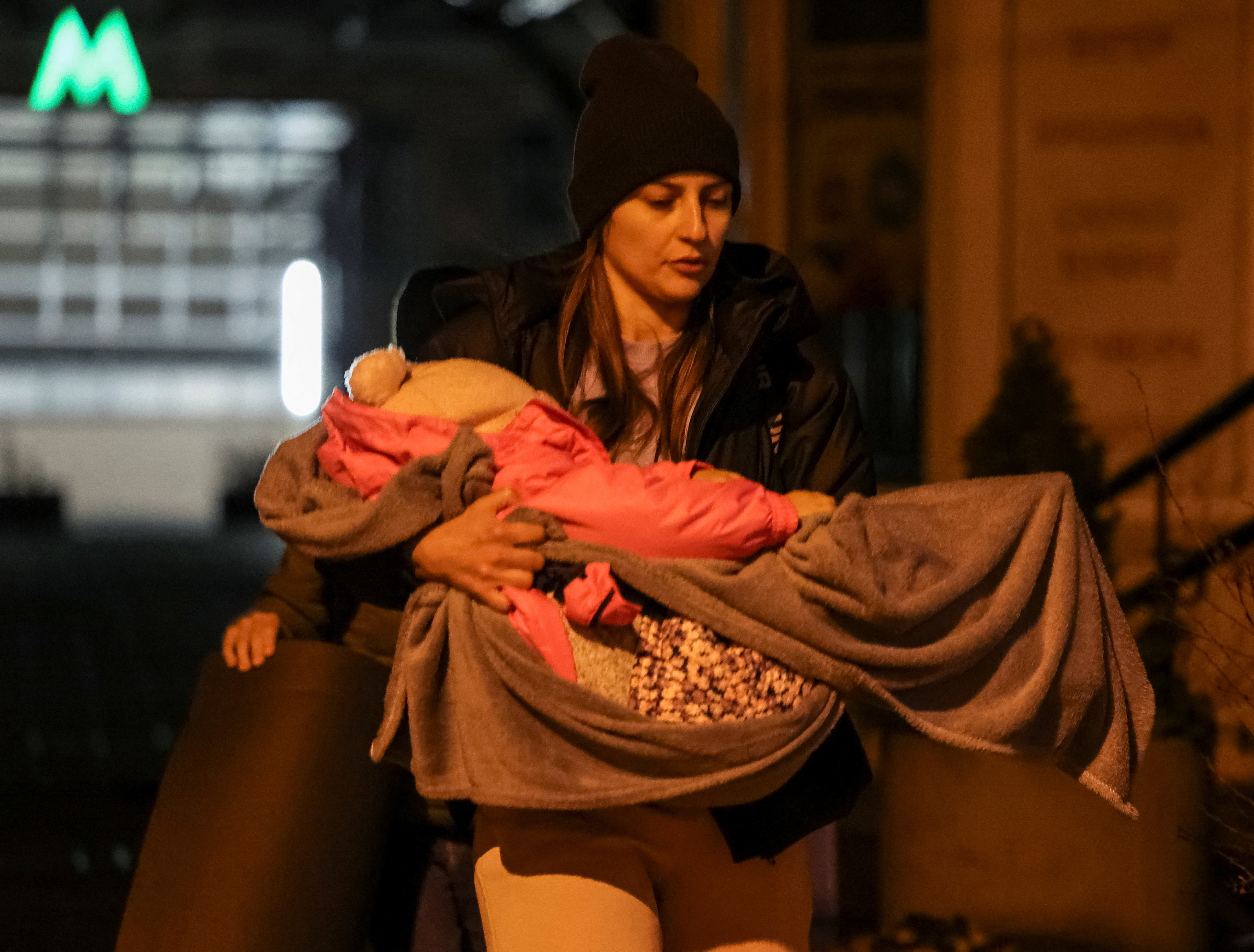 A woman carries her baby as she comes back from a shelter inside a metro station.