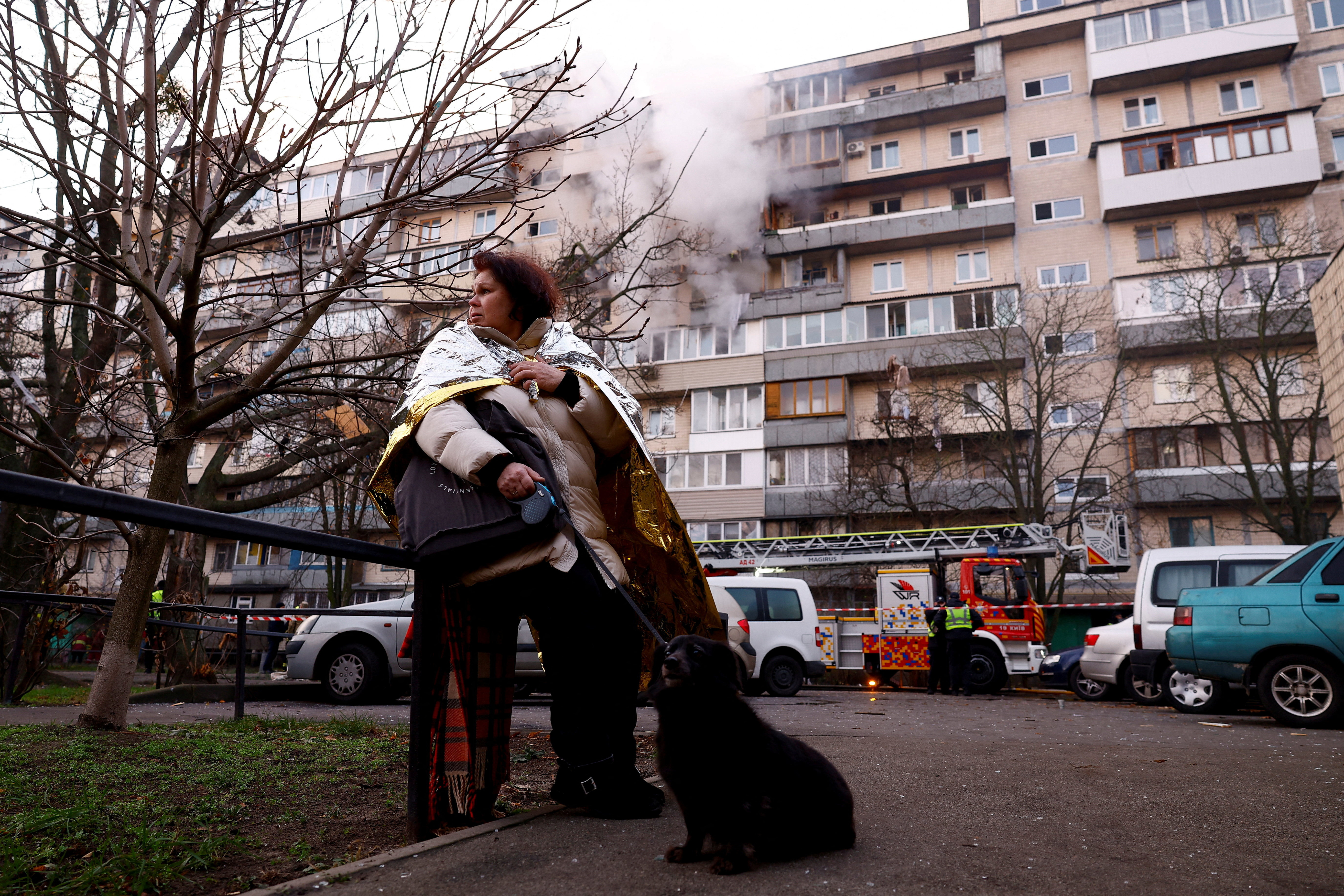 A woman stands with a dog next to the site of an apartment building hit during an overnight Russian drone and missile strike, amid Russia's attack on Ukraine, in Kyiv, Ukraine, November 14, 2025. REUTERS/Valentyn Ogirenko TPX IMAGES OF THE DAY