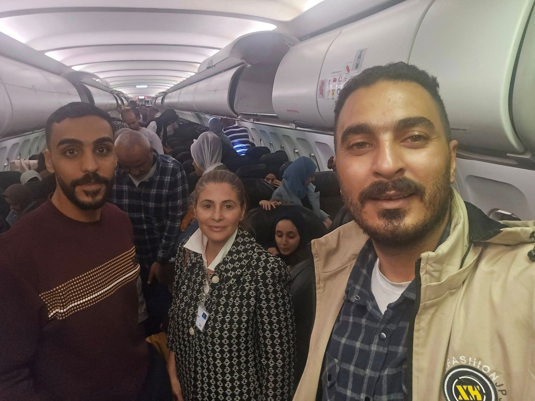 Hanan Jarrar, Palestinian ambassador to South Africa, smiles for a picture on the plane with several passengers.
