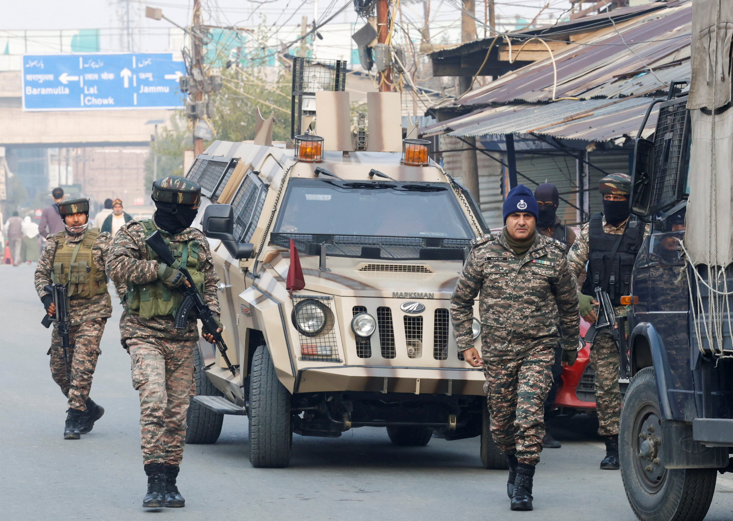 Indian security forces walking in front of a military jeep.