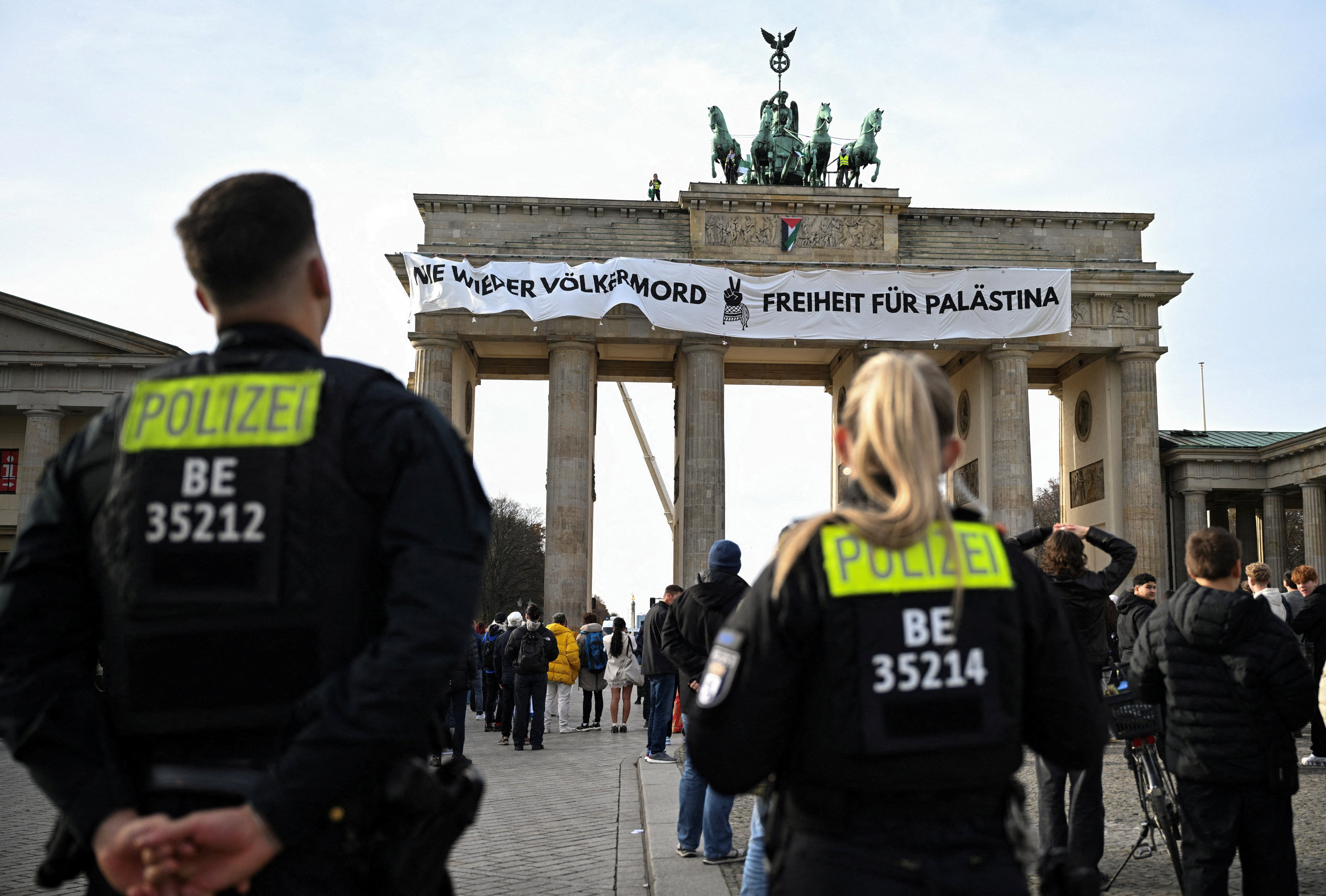 German police officers stand in front of the Brandenburg Gate as pro-Palestinian protesters wave flags of Palestine and unveiled a placard reading, &ldquo;Never again genocide - Freedom for Palestine&rdquo;, on top of Brandenburg Gate in Berlin, Germany, November 13, 2025. [Annegret Hilse/File Photo/Reuters]