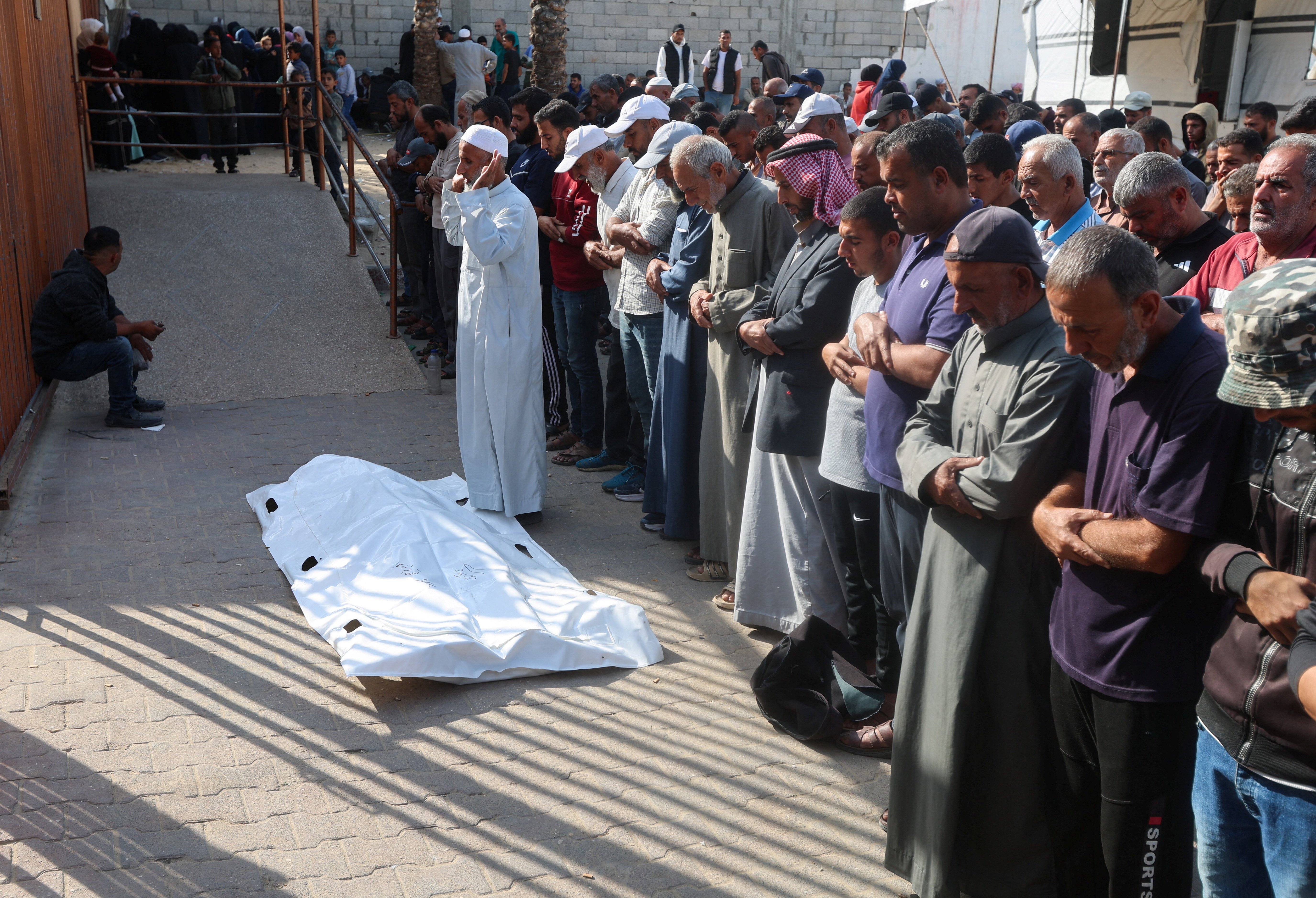 Mourners pray next to the body of one of two Palestinians killed by Israeli fire in Khan Younis in the southern Gaza Strip, November 24, 2025. [Ramadan Abed/Reuters]