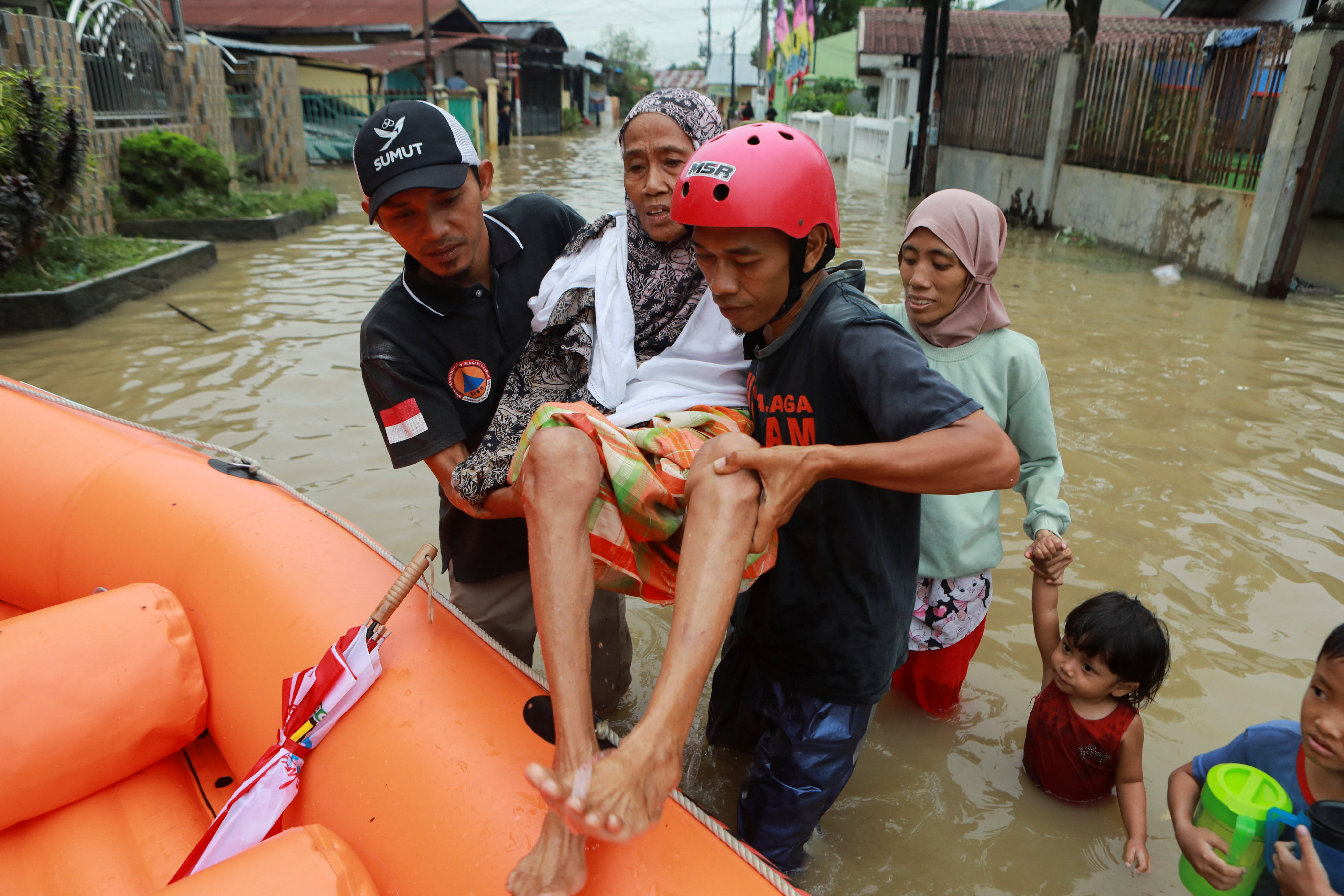 Rescuers evacuate an elderly woman from a flooded area.