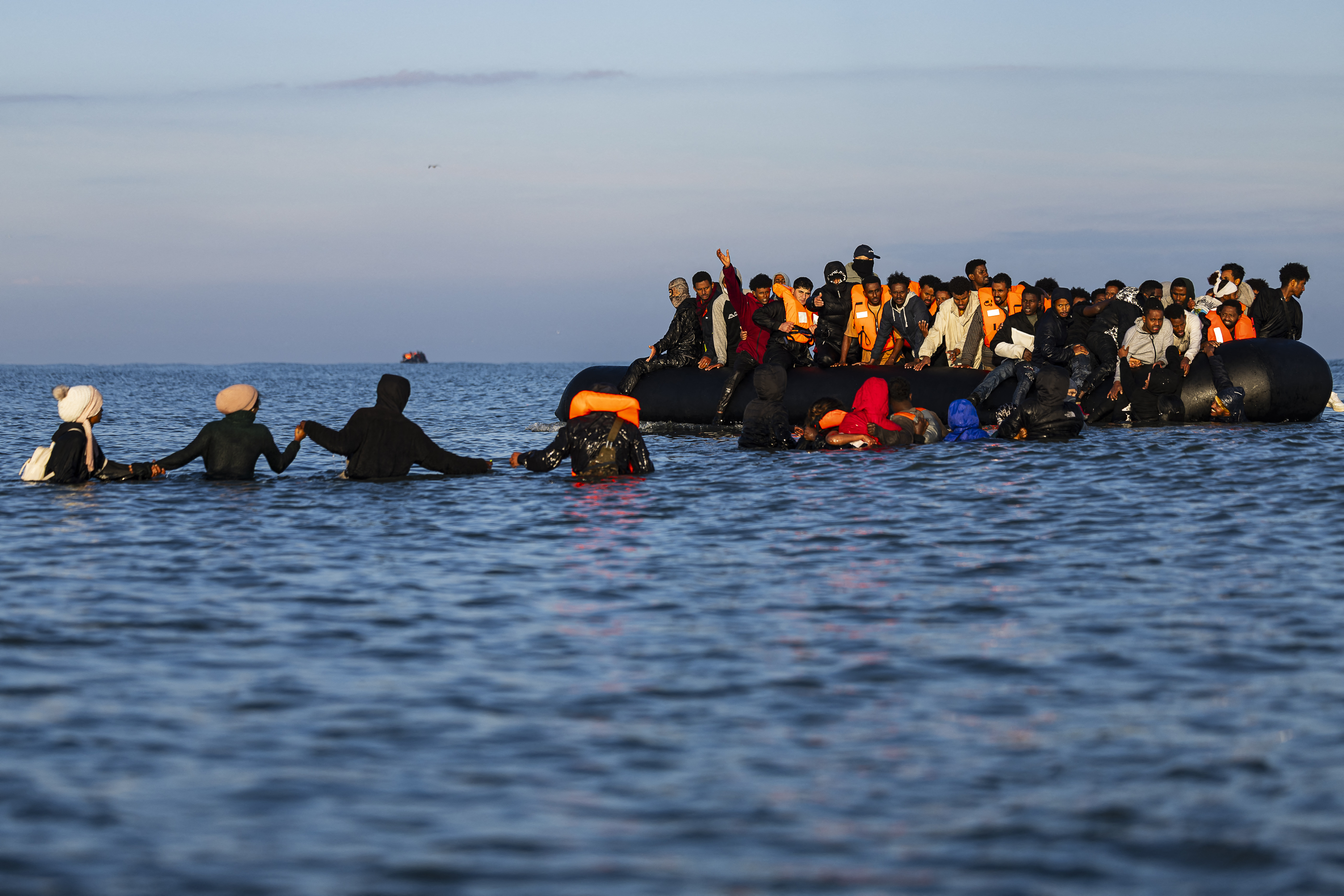 Migrants wade into the sea to try to board smugglers' boats in an attempt to cross the English Channel off the beach of Gravelines, northern France on September 27, 2025.