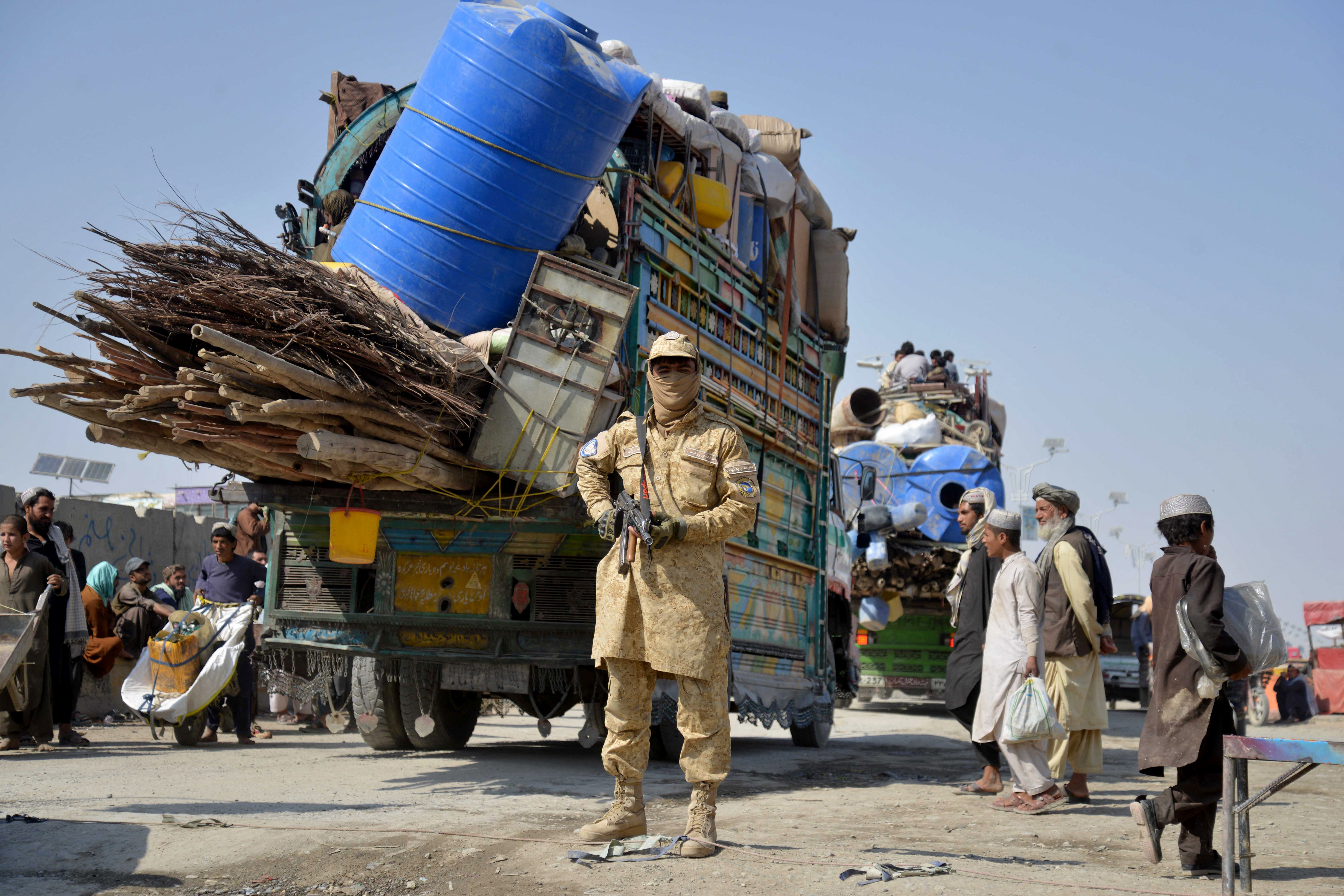 A Taliban security person stands guard as deported Afghan refugees from Pakistan arrive at the border crossing