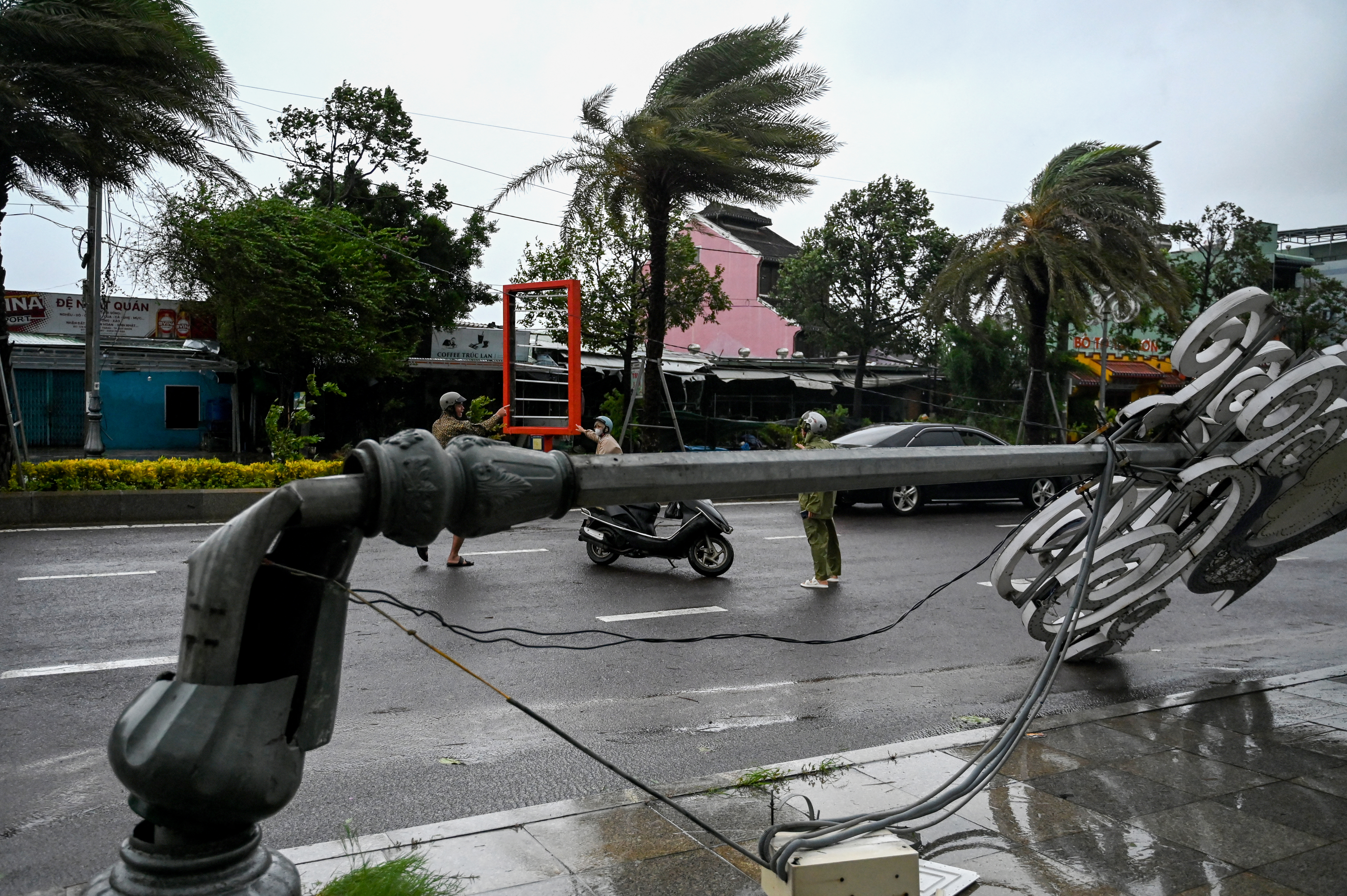 Residents make their way past a lamp post that collapsed in strong winds ahead of the arrival of Typhoon Kalmaegi near Quy Nhon beach in Gia Lai province in central Vietnam [Nhac Nguyen/AFP]