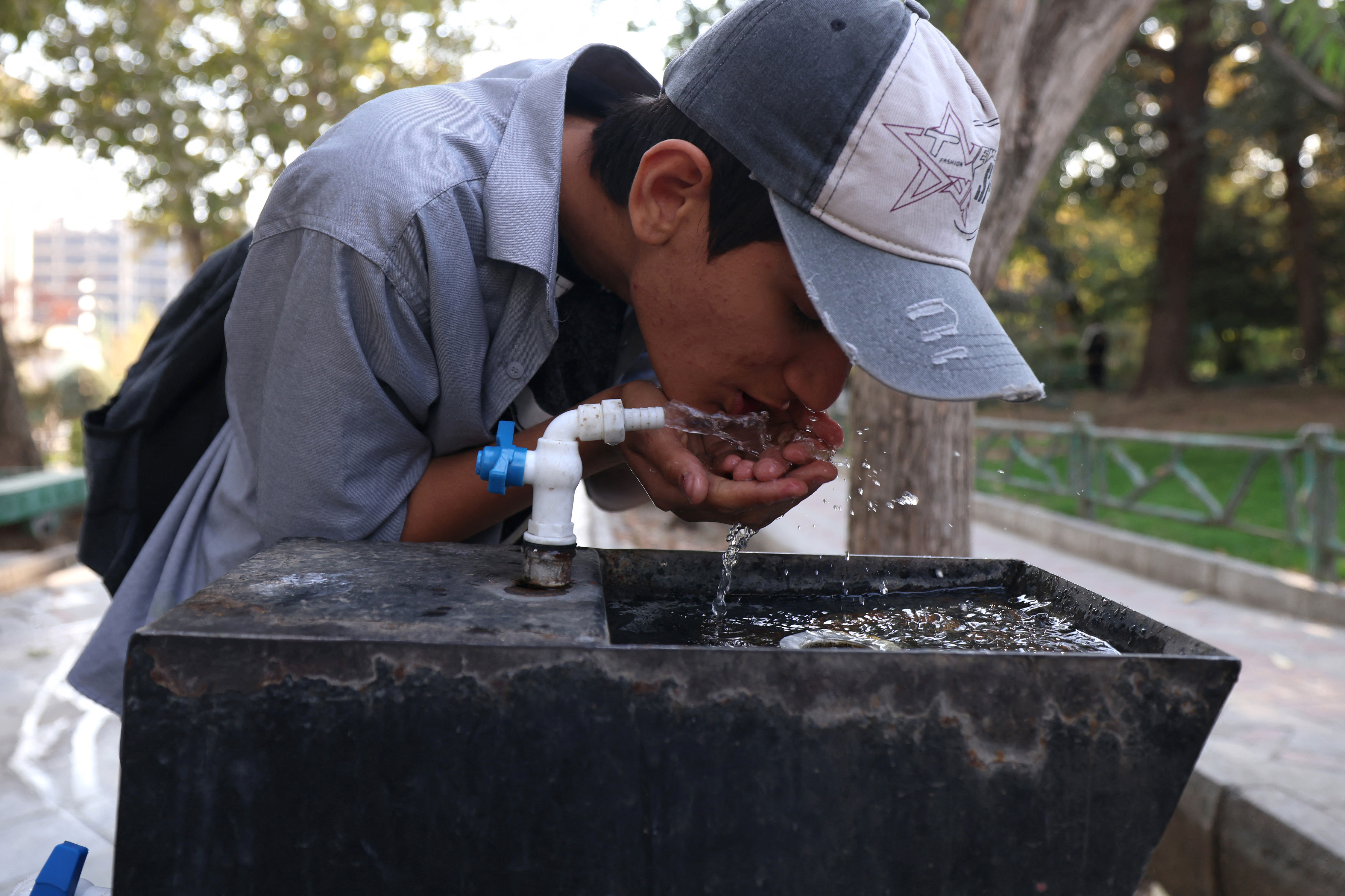 A youth drinks water from a fountain in Mellat Park, as the Iran faces sever water shortages, in Tehran on November 9, 2025. [Atta Kenare/AFP]