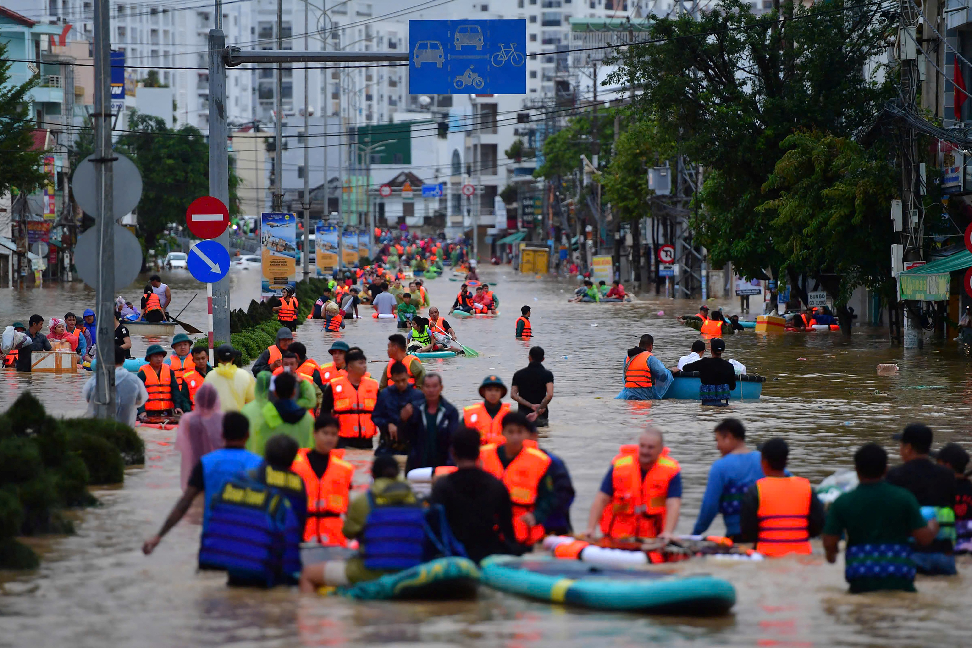People wade through floodwaters in a street.