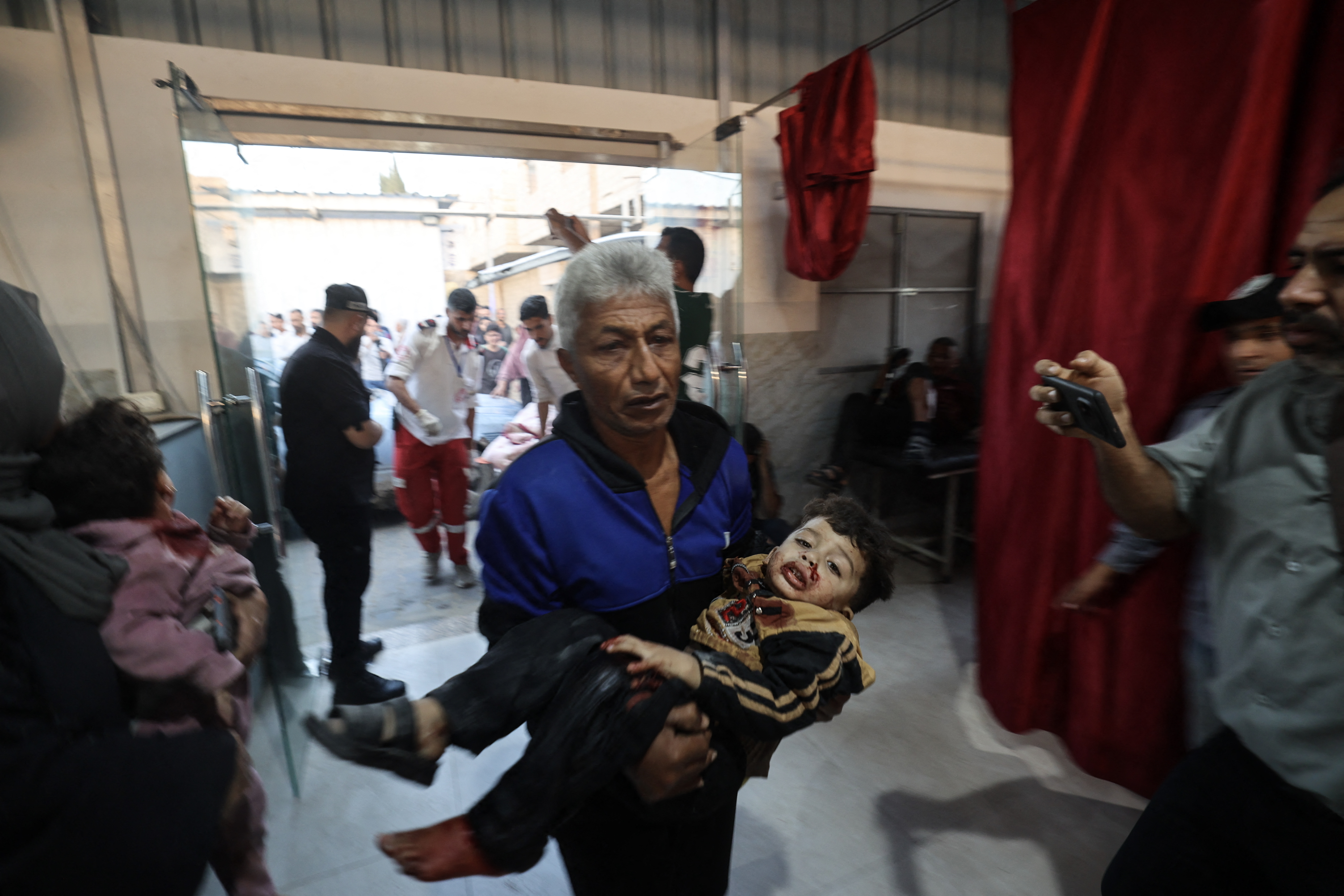 A Palestinian man carries an injured child at a hospital.