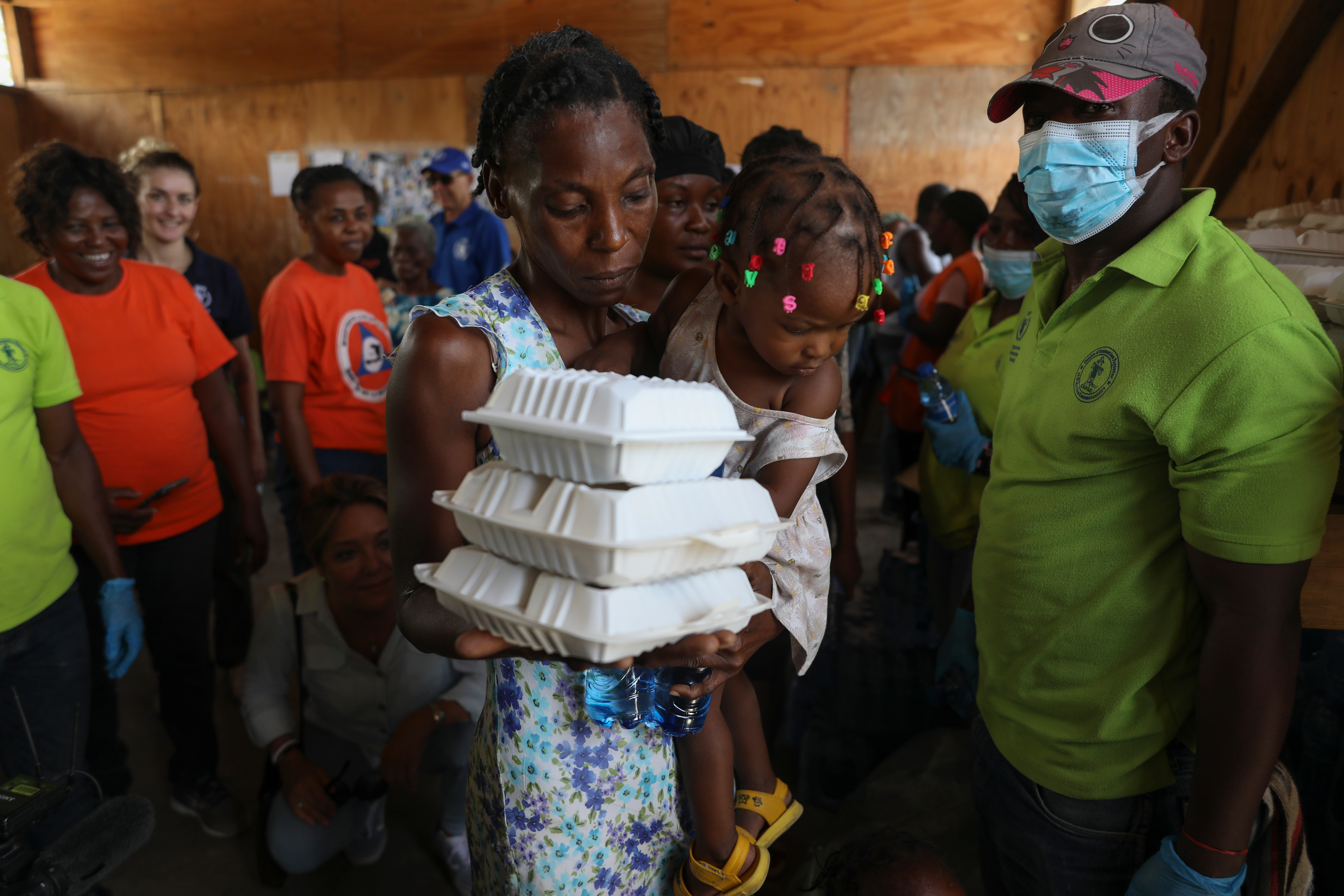 A woman walks away from a World Food Programme event at a high school with a stack of three takeout food containers
