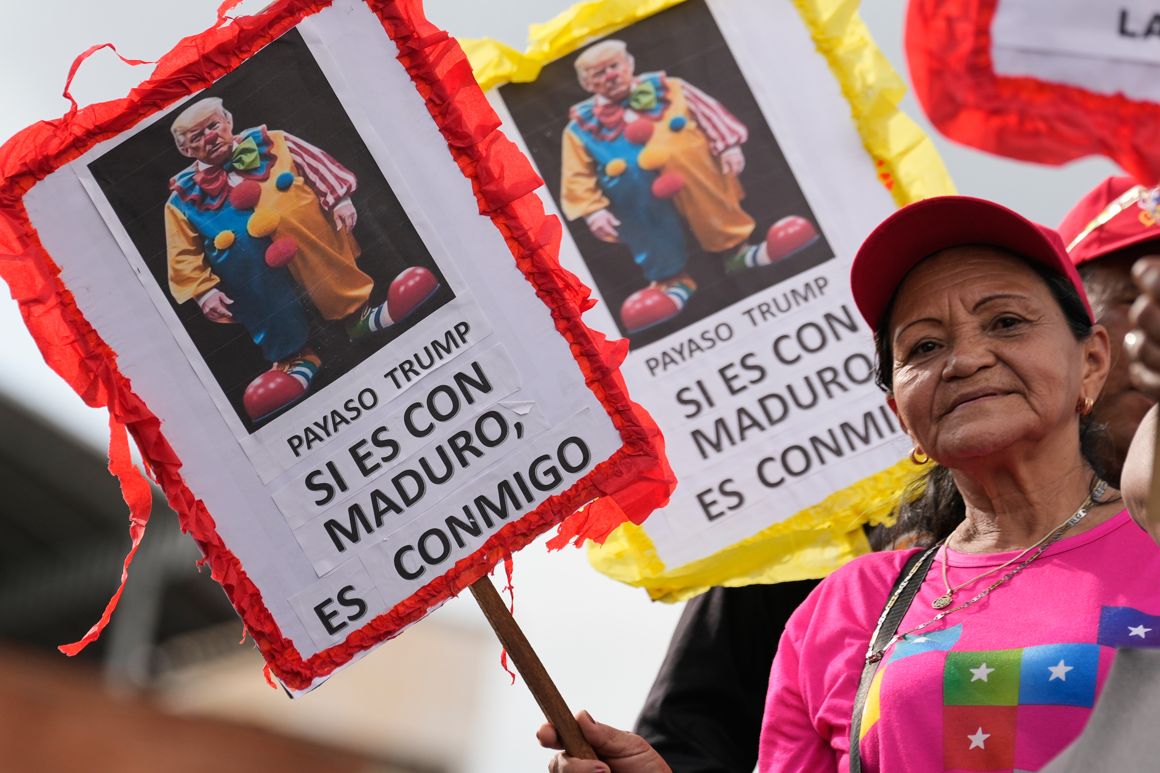 A woman holds up a sign that reads in Spanish, "Clown Trump, if you're against Maduro, you're against me"