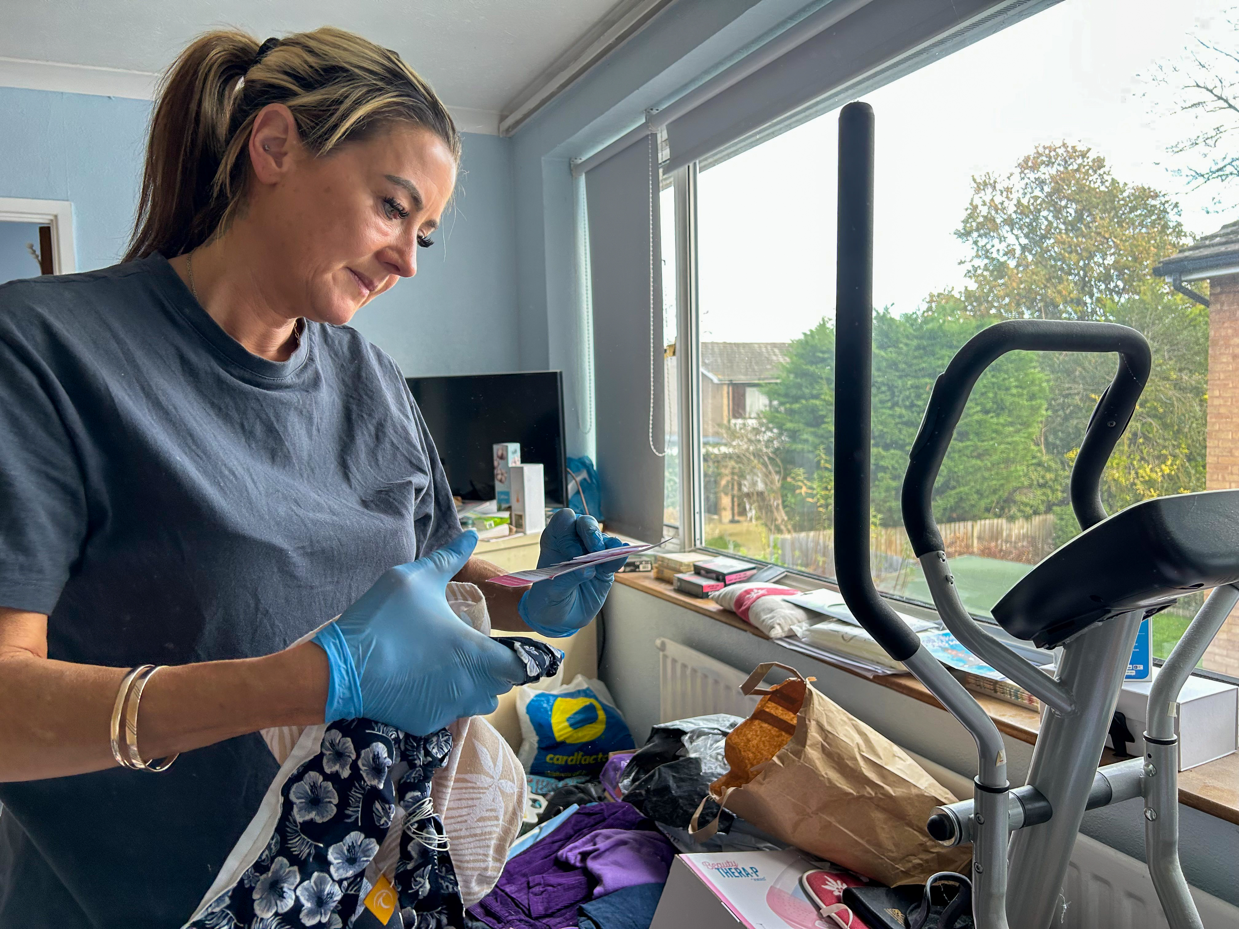 Jo Powell carefully goes through items in a hoarder's bedroom, ensuring that nothing important gets thrown away. [Amandas Ong/Al Jazeera]